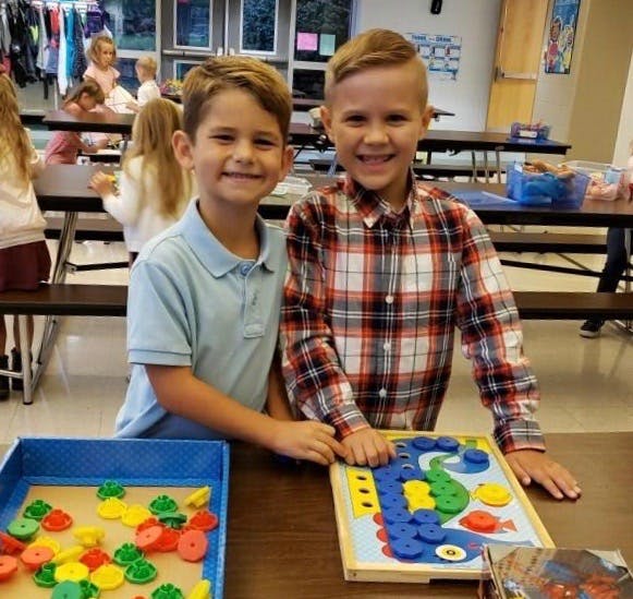Two children standing at a table with a game