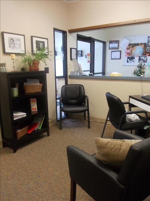 Waiting room with a small black bookshelf, chairs, and a reception desk