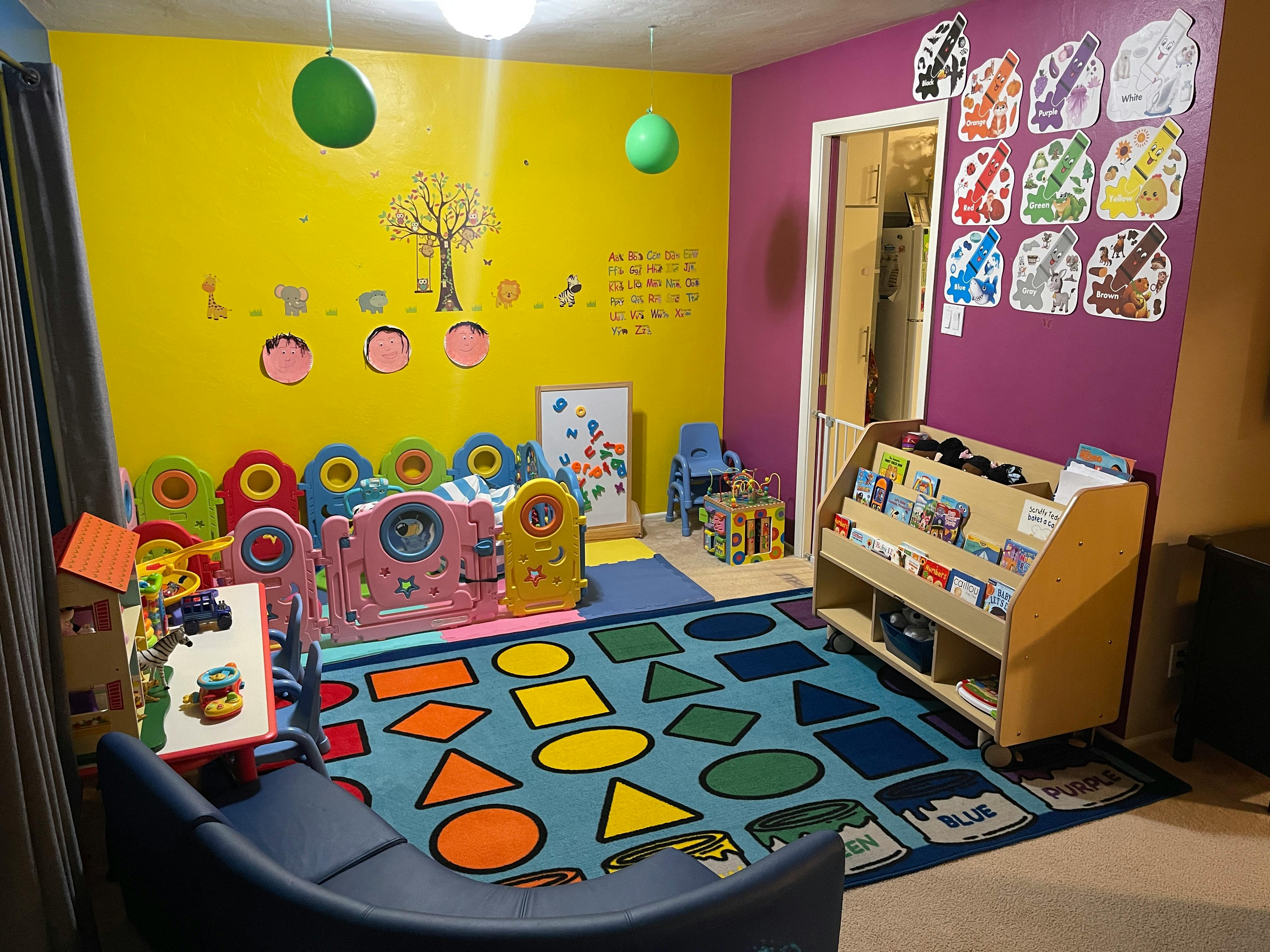 Playroom with colorful rug, toys, and book display