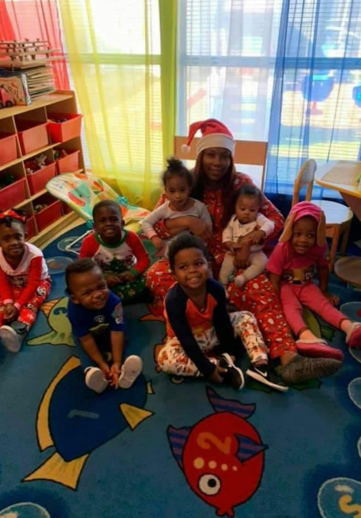 Person in Santa hat with multiple children in a classroom