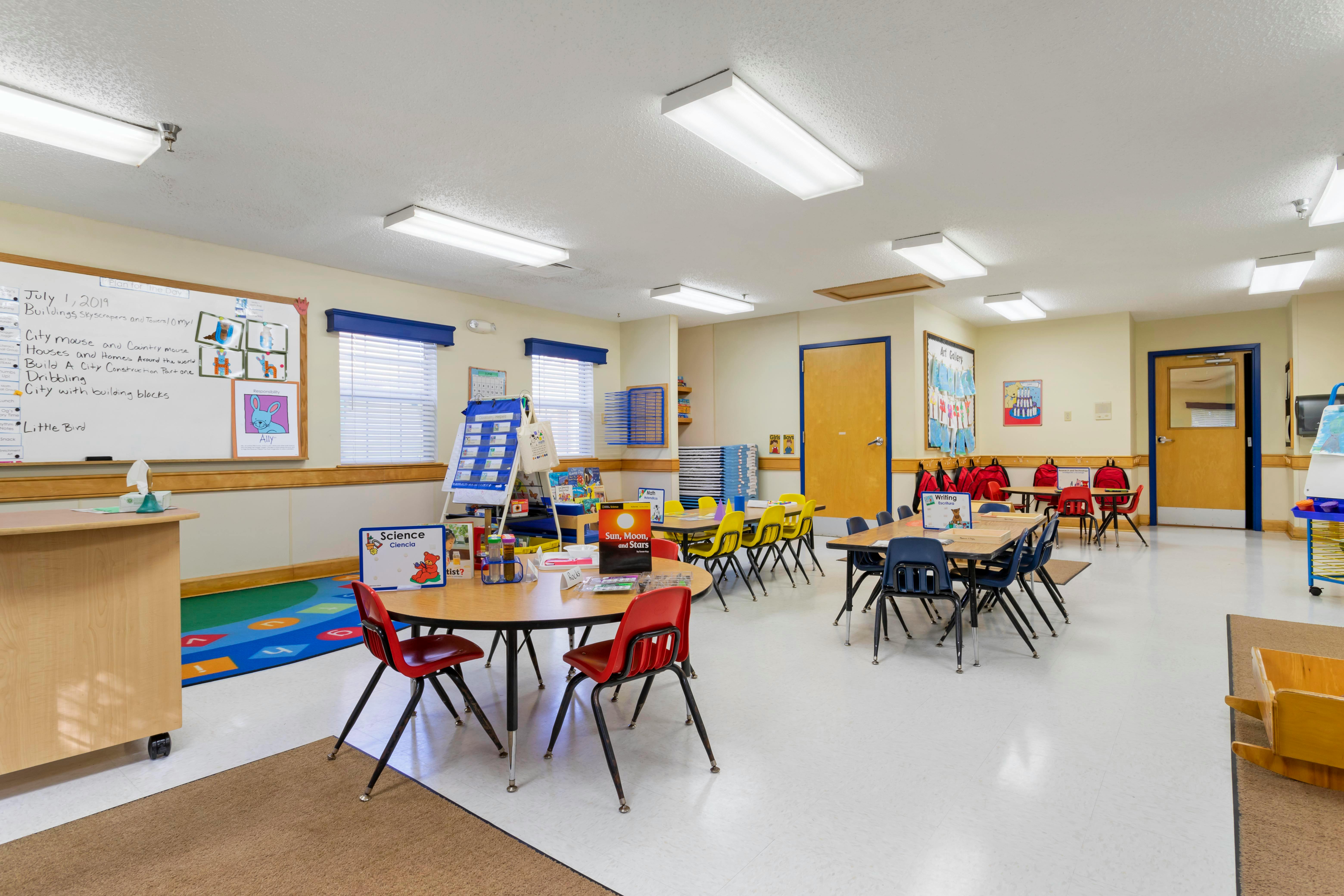 Classroom with child-sized tables and chairs, whiteboards, and learning materials
