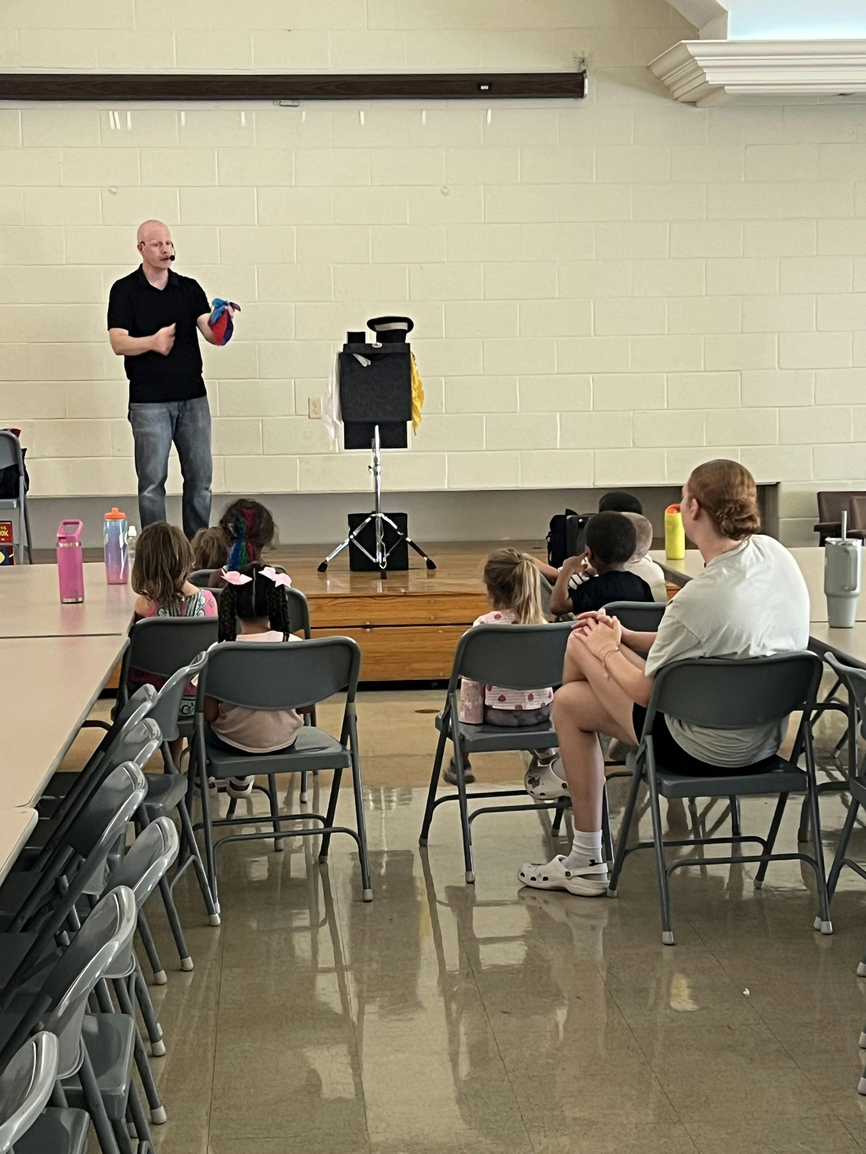 Person performing magic for an audience of children and adults