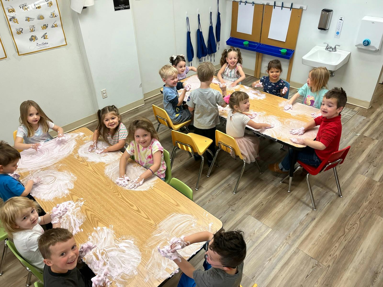 Children at tables playing with a white, foamy substance