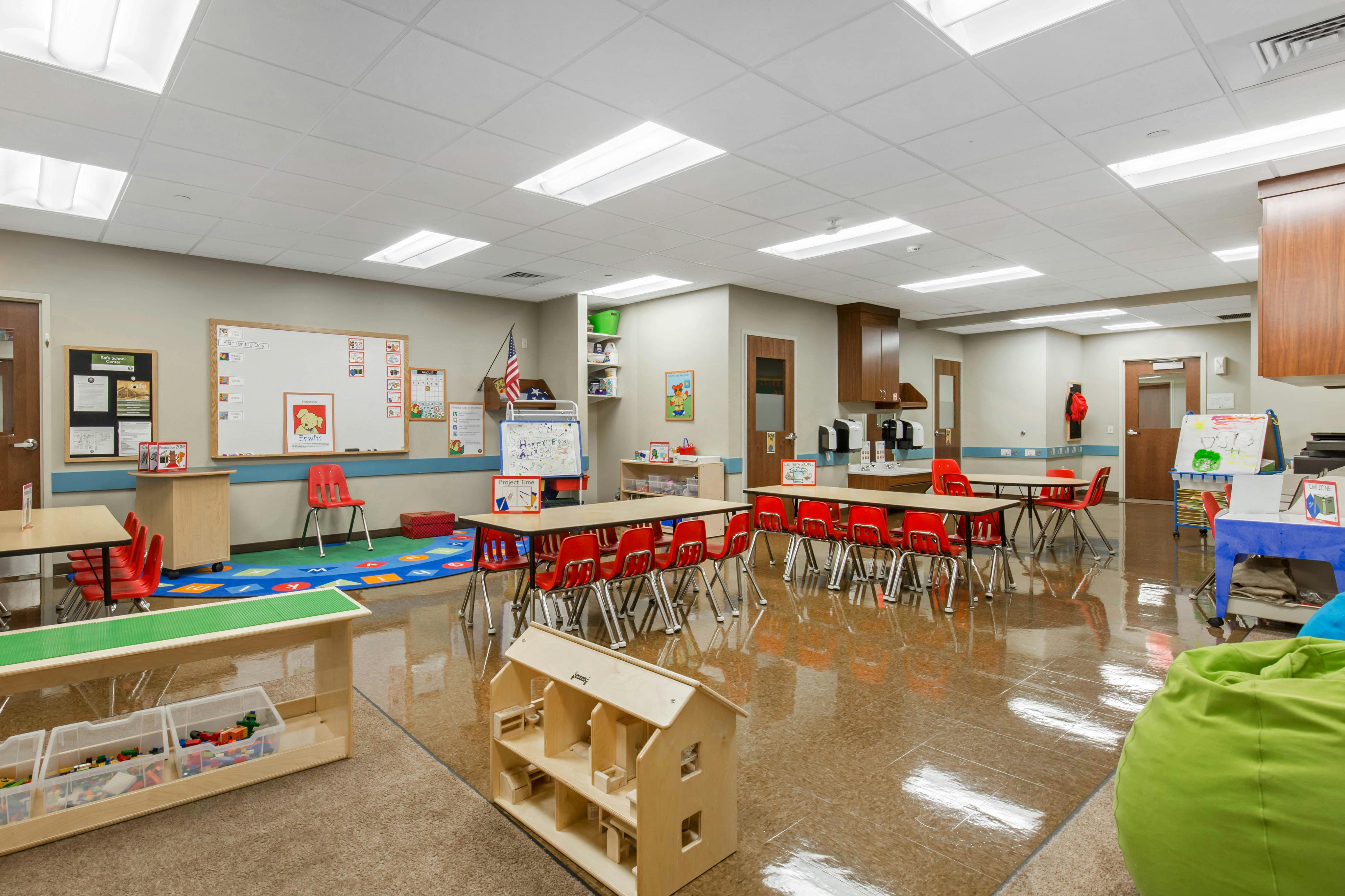 Classroom with tables, red chairs, and various educational displays