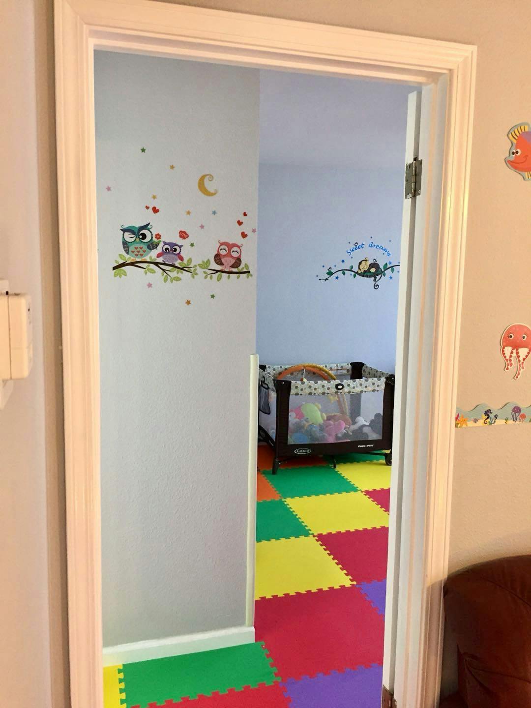 Doorway leading to a room with a playpen and colorful floor mats