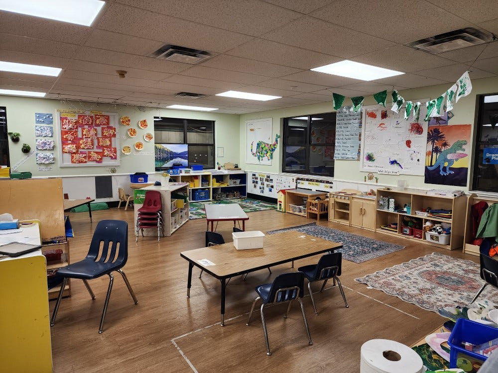 Classroom with small tables, chairs, and children's artwork on the walls