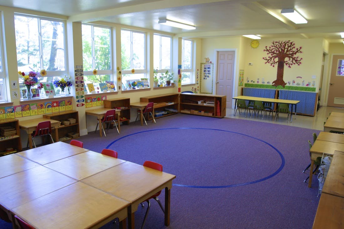 Classroom with small tables and chairs, purple rug with a blue circle