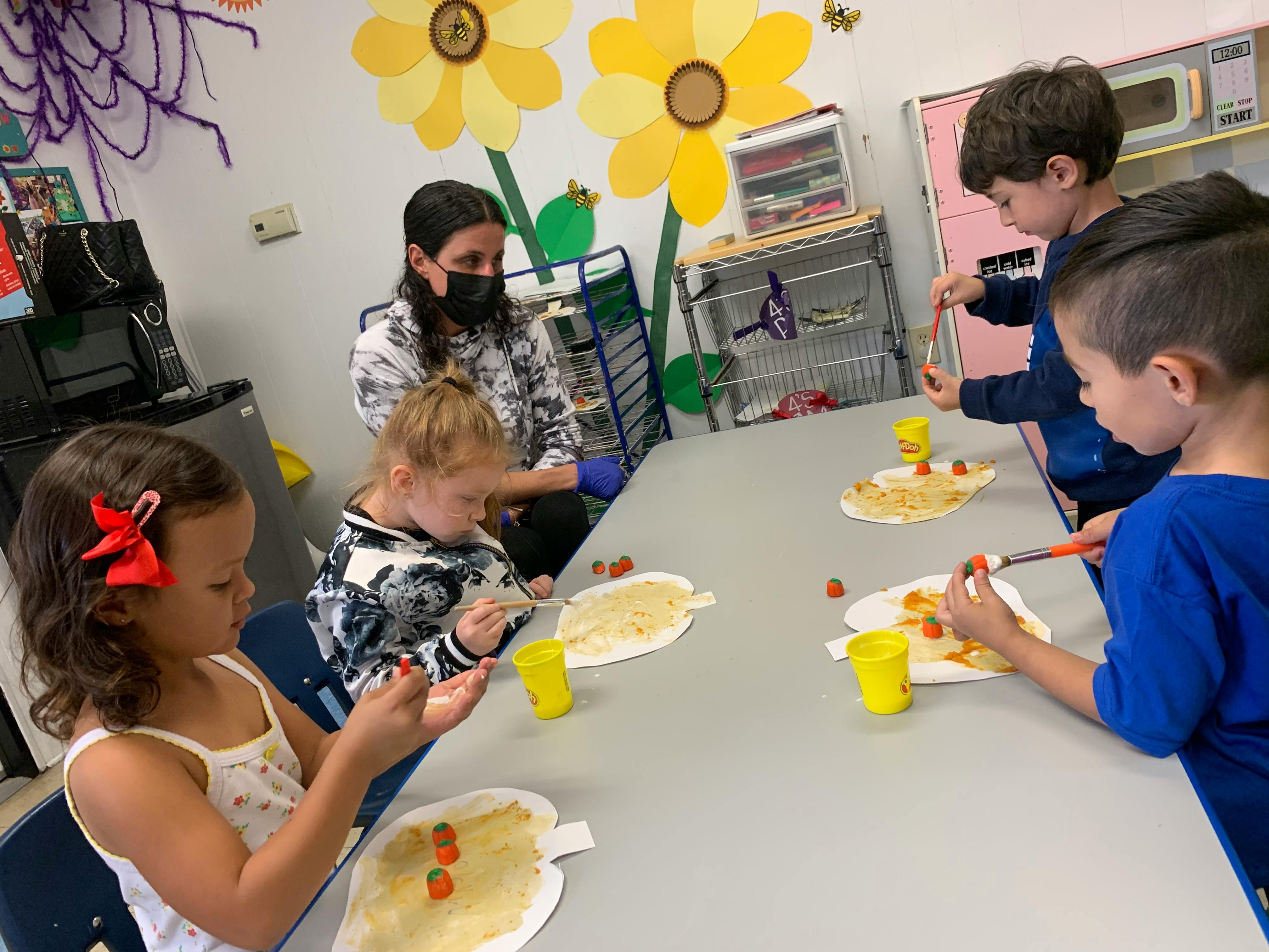 Adult and children at a table decorating paper cutouts