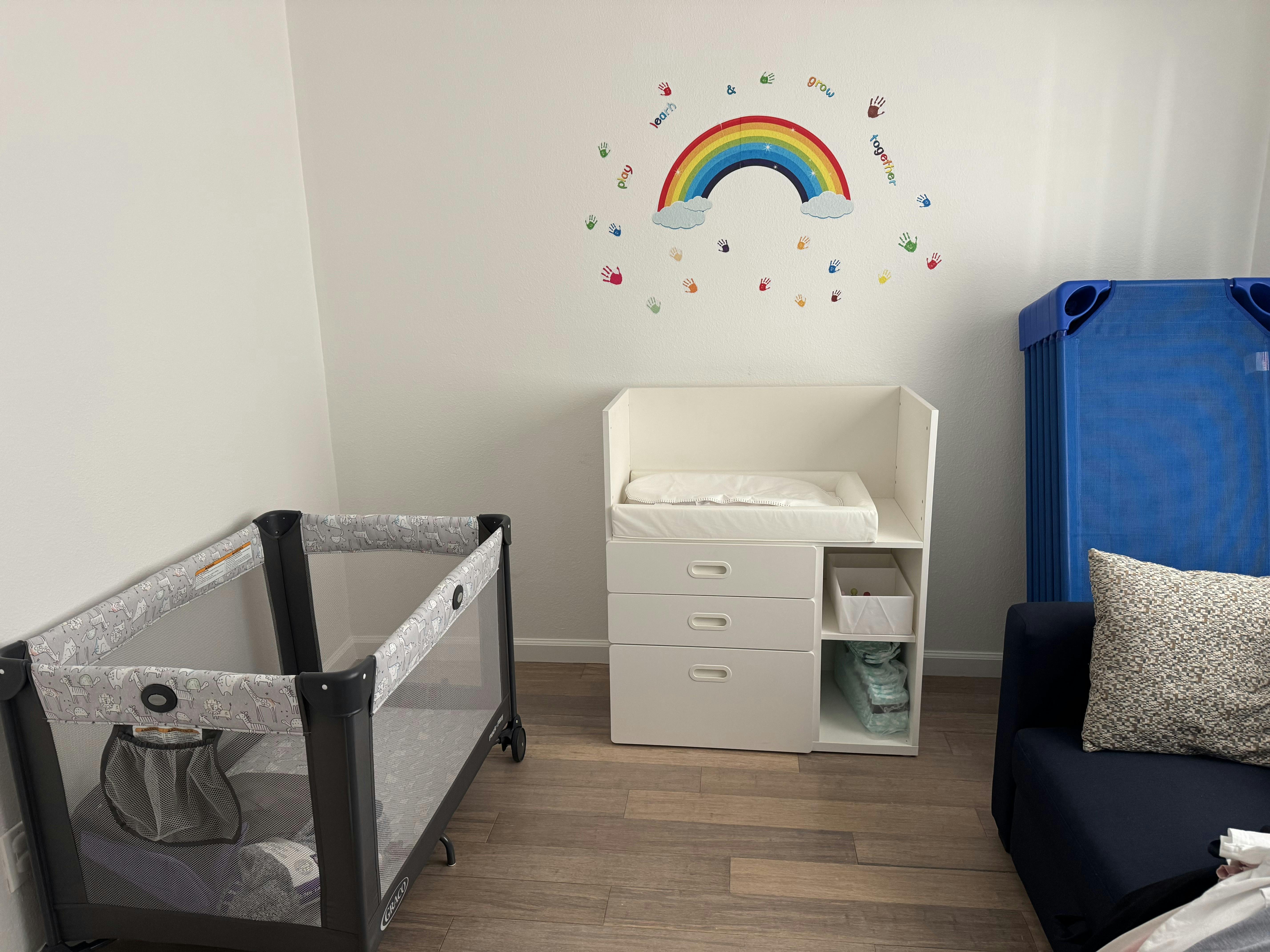 Nursery room with a crib, changing table, and rainbow wall decal