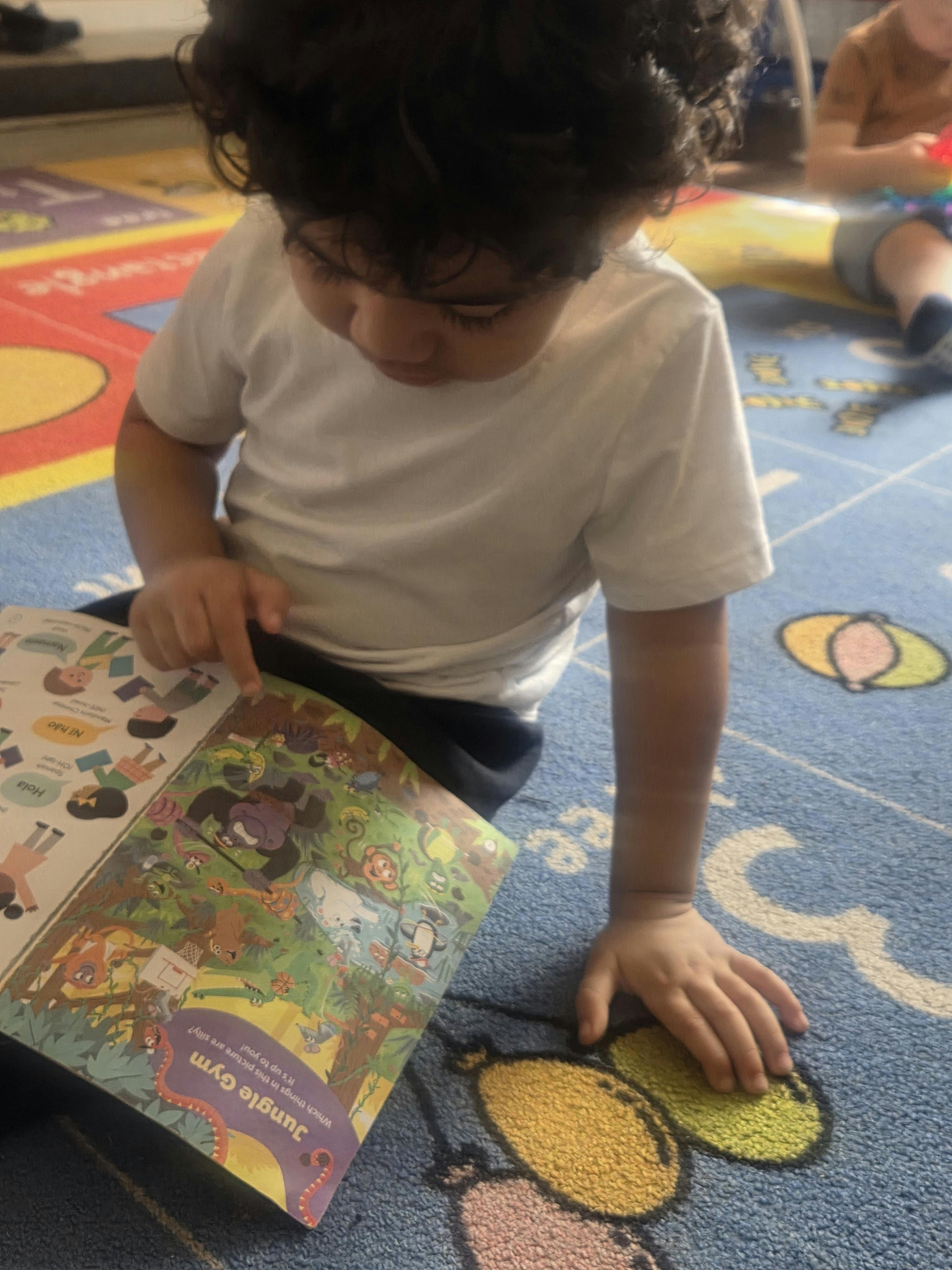 Child reading a book on a classroom rug