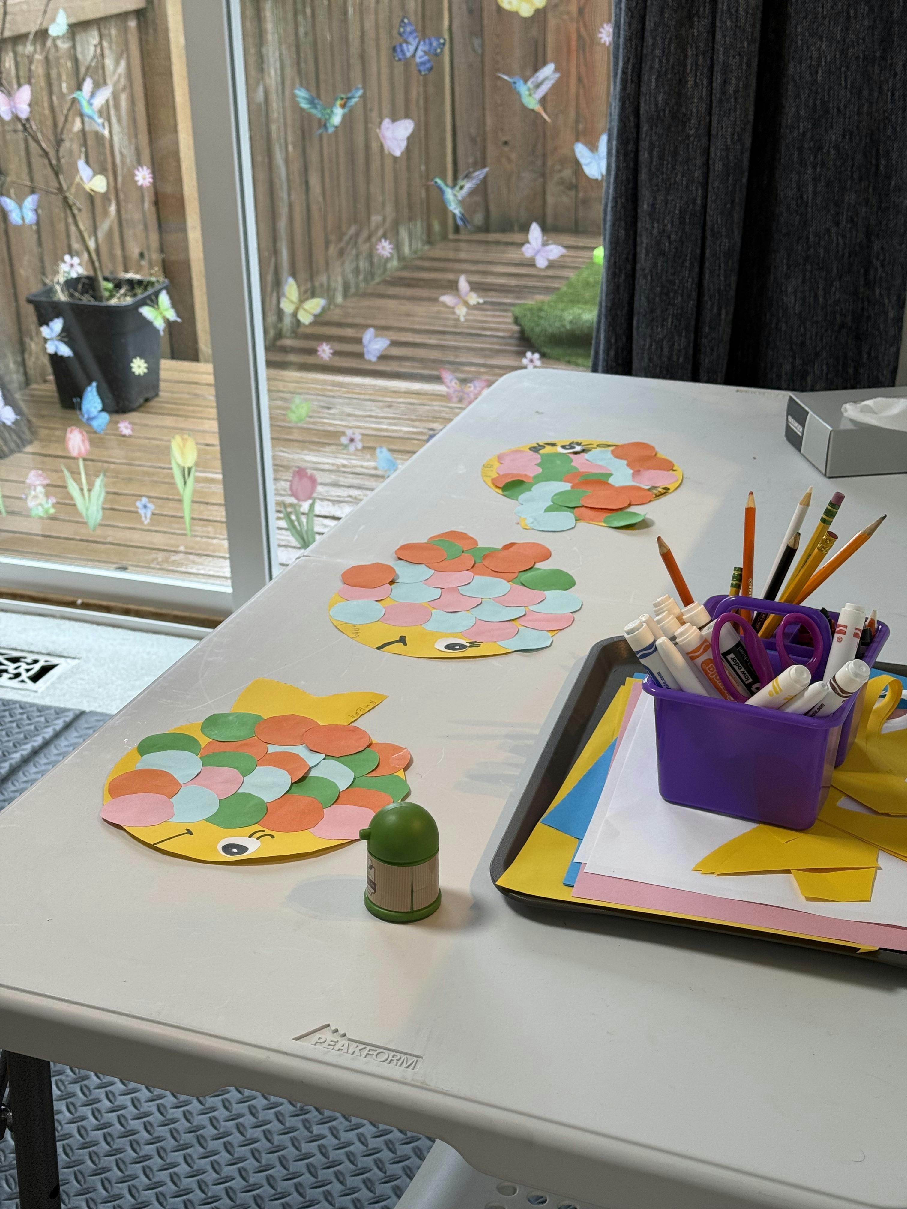 Crafts on a table next to a window with butterfly decorations