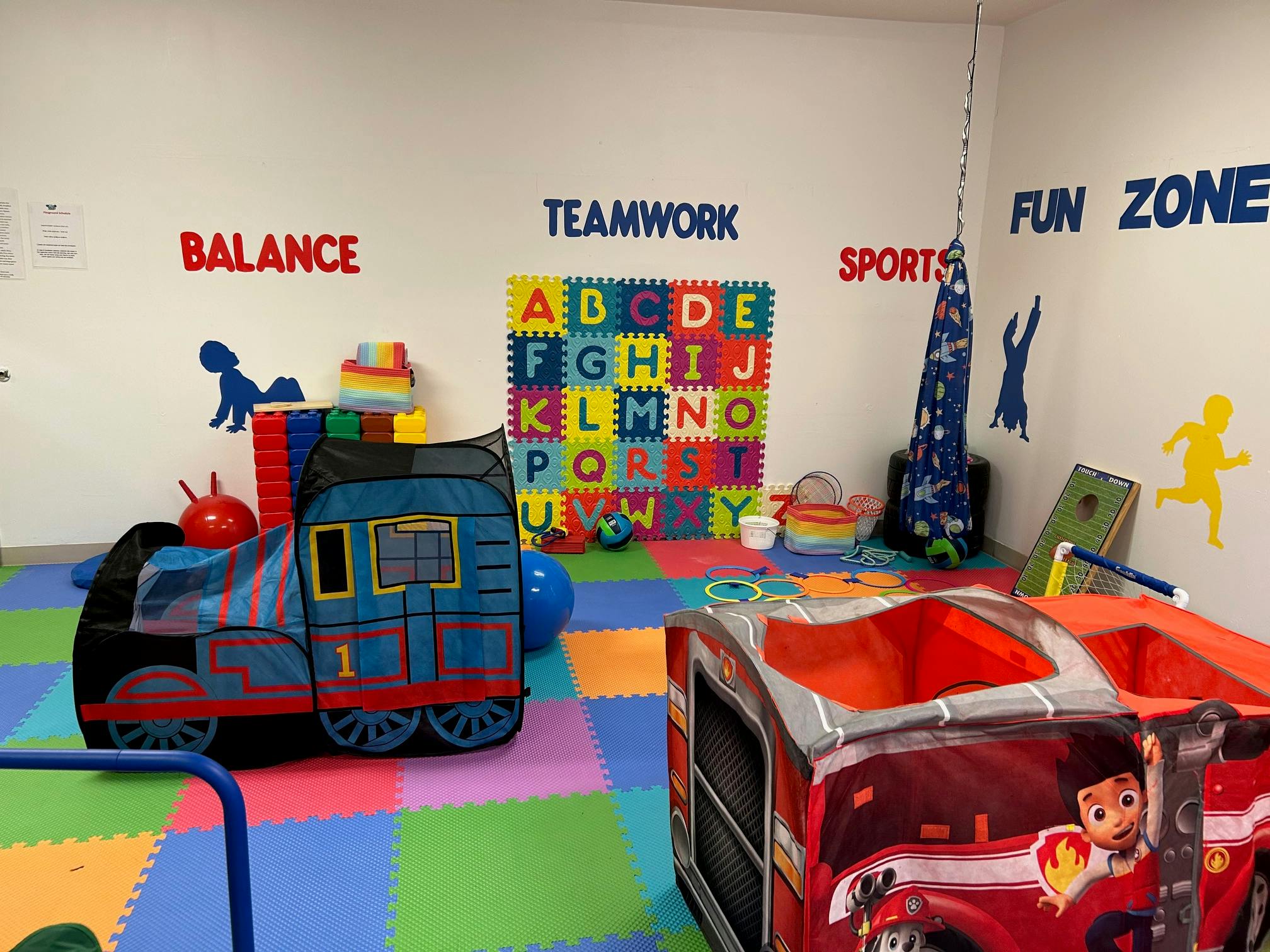 Playroom with colorful floor mats, toy train, and alphabet puzzle
