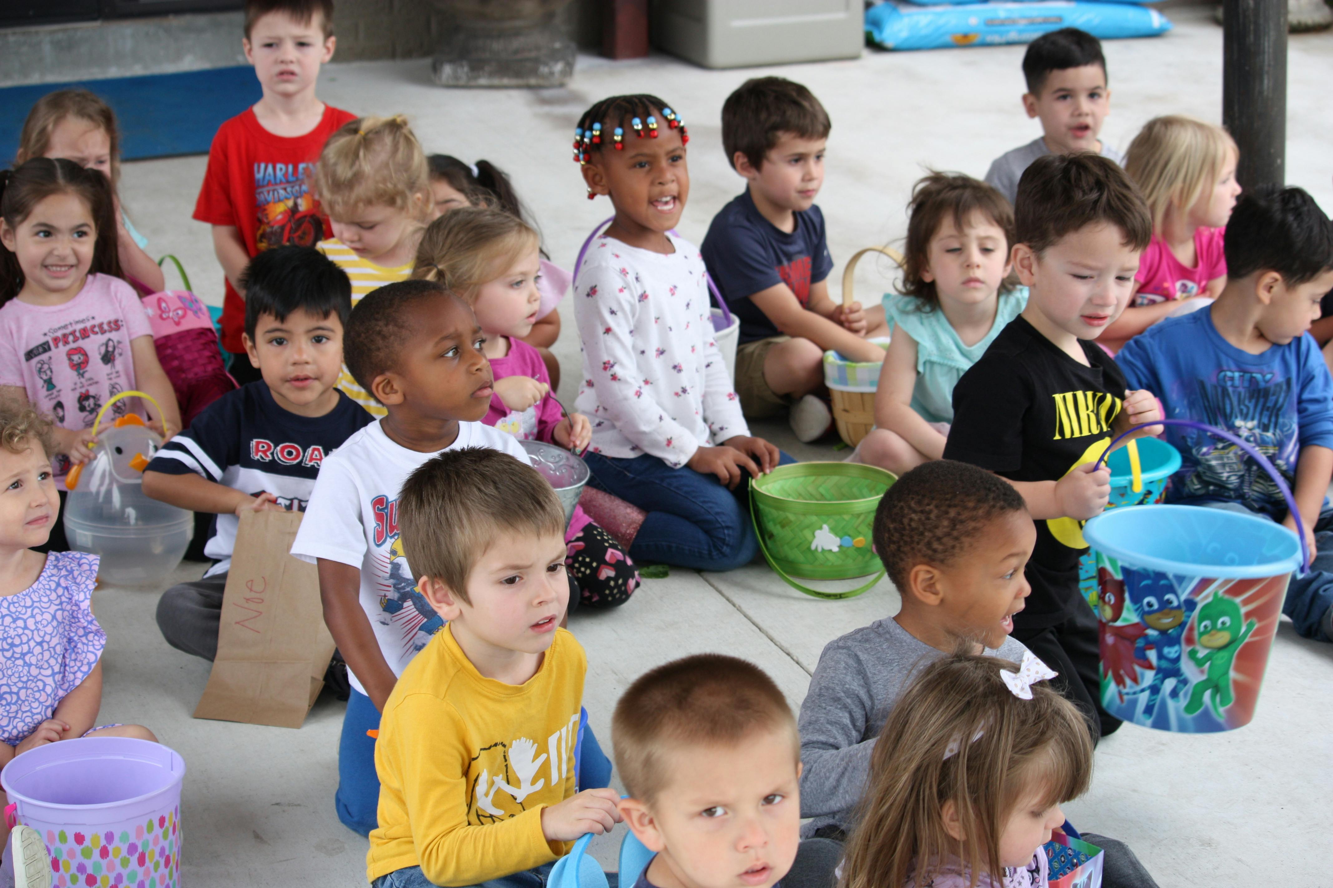 Group of children holding Easter baskets while sitting on the ground