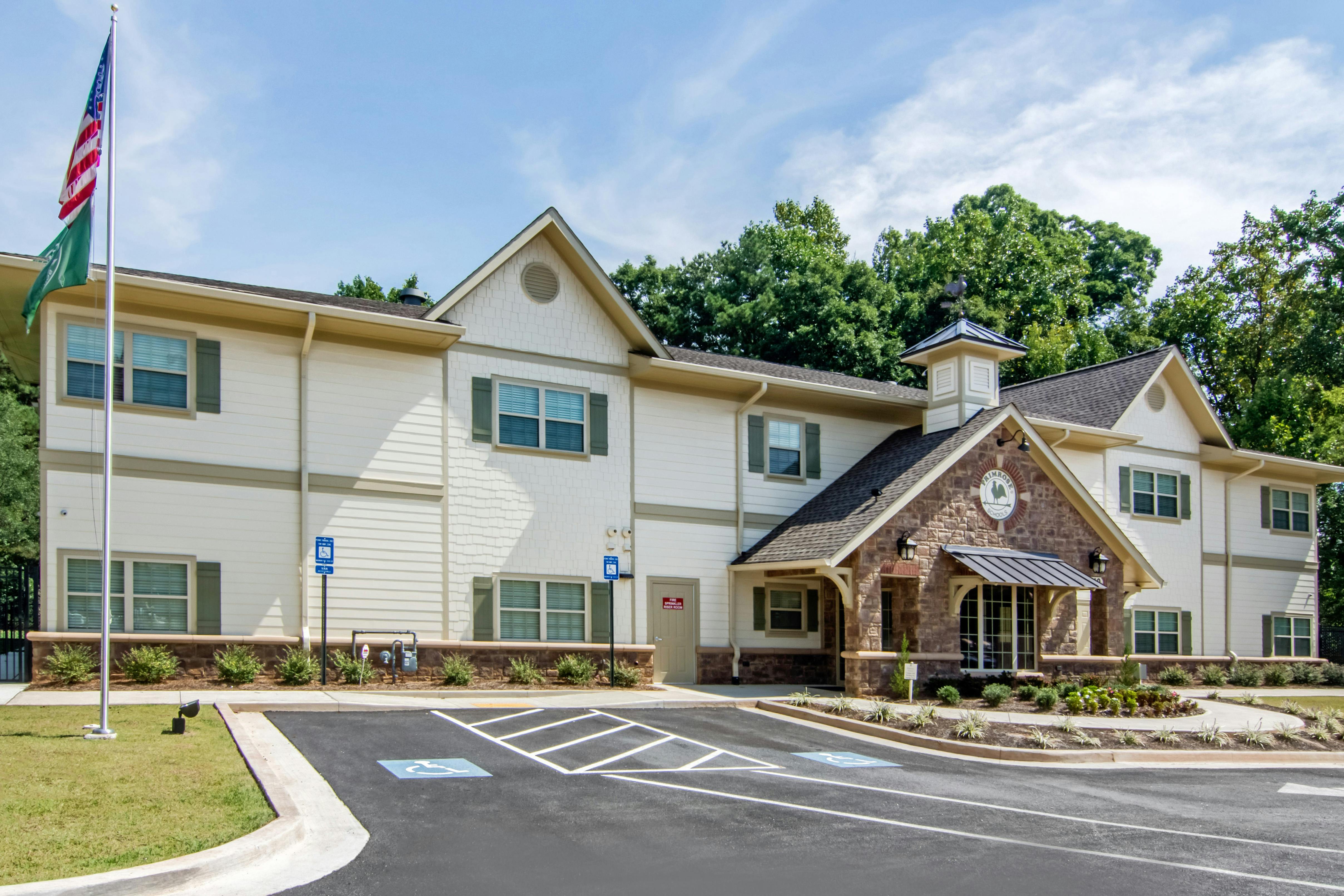 A beige and brick building with multiple windows and a parking lot with accessible parking
