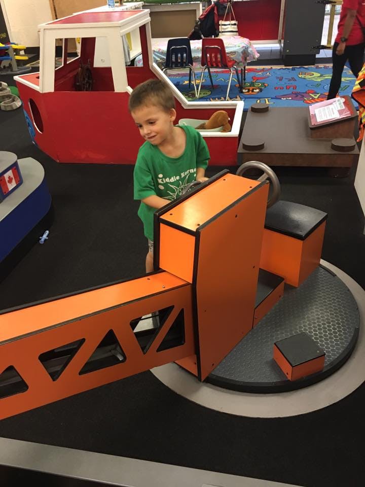 Child playing with an orange toy crane