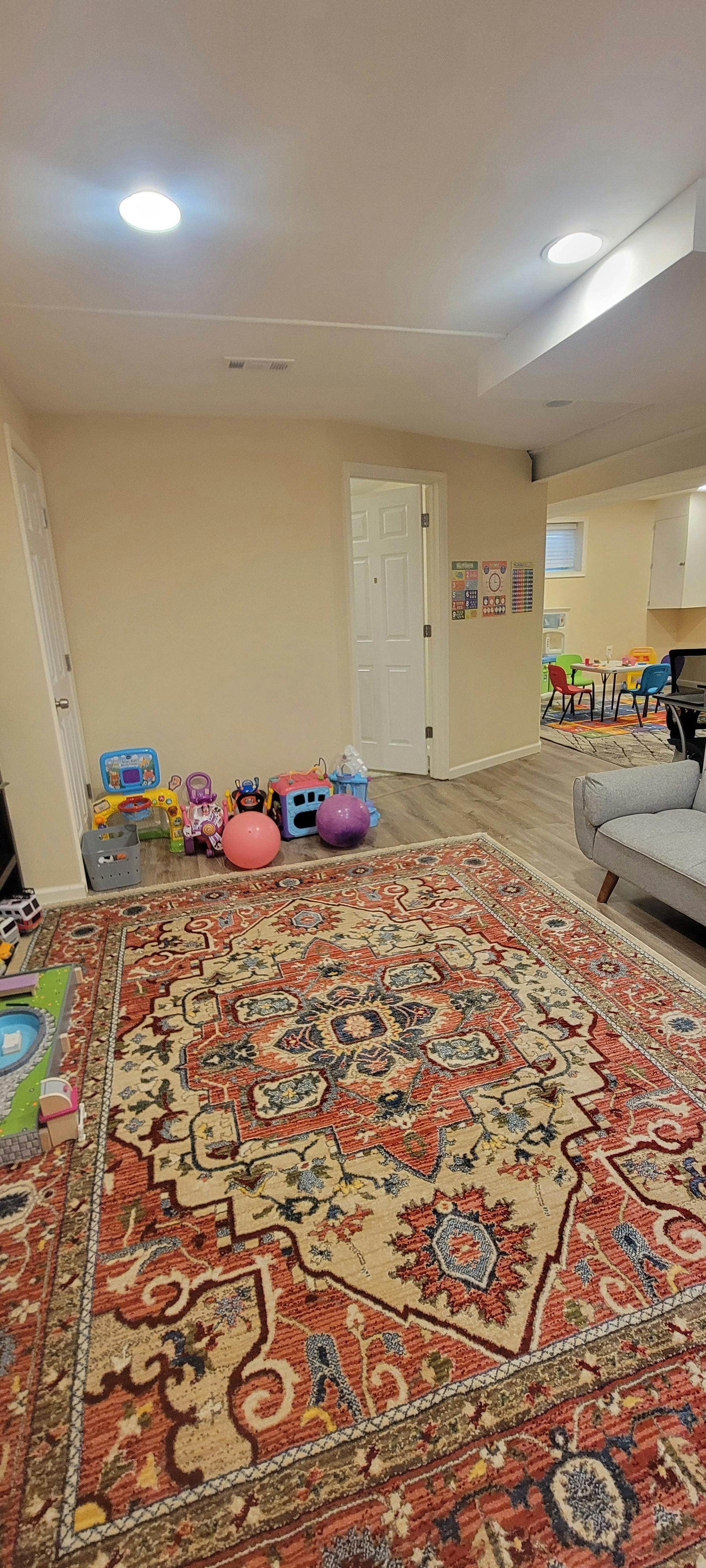 Play area with children's toys and a decorative rug in a home room