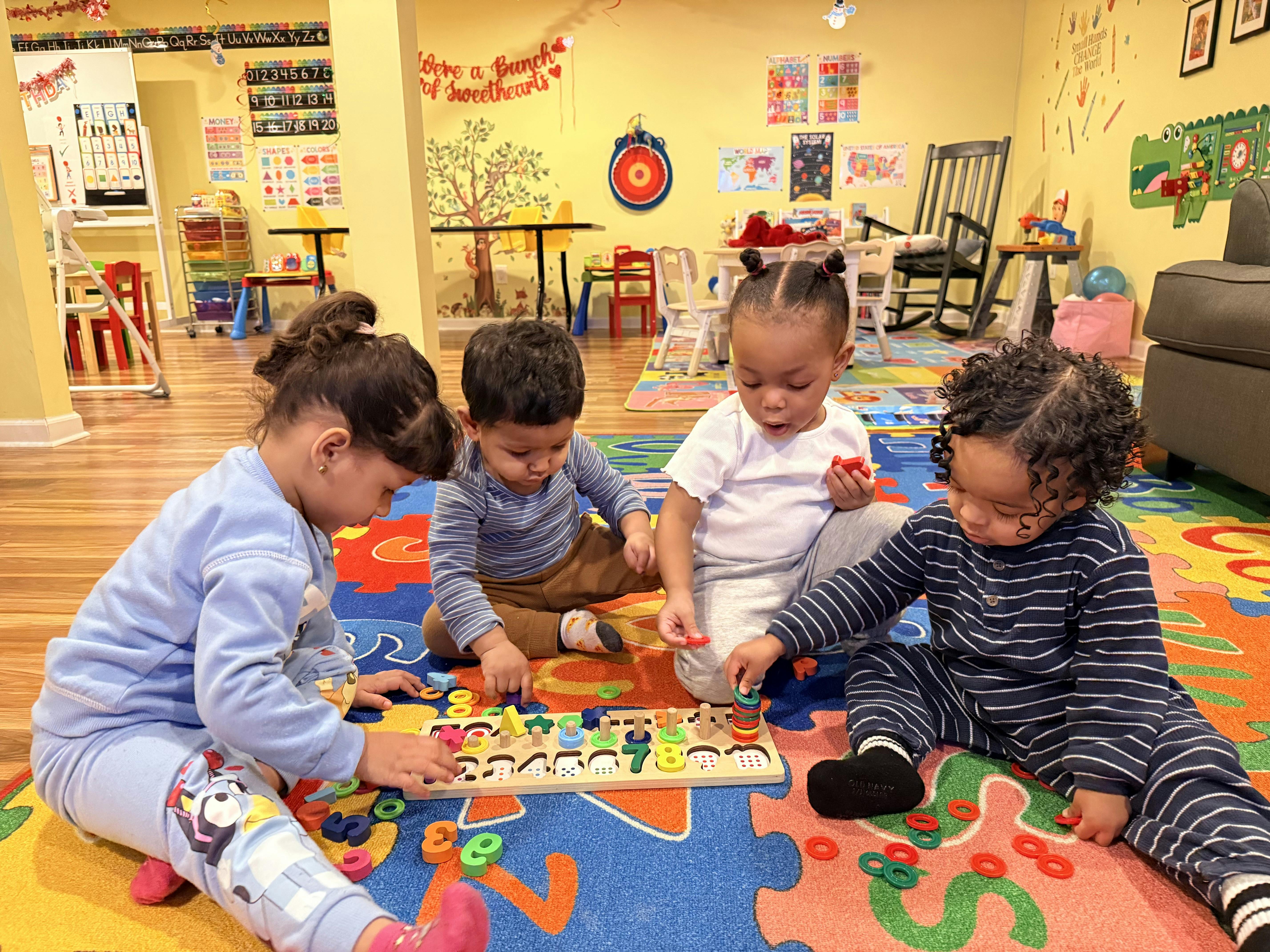 Four children playing with a wooden peg board and colorful rings