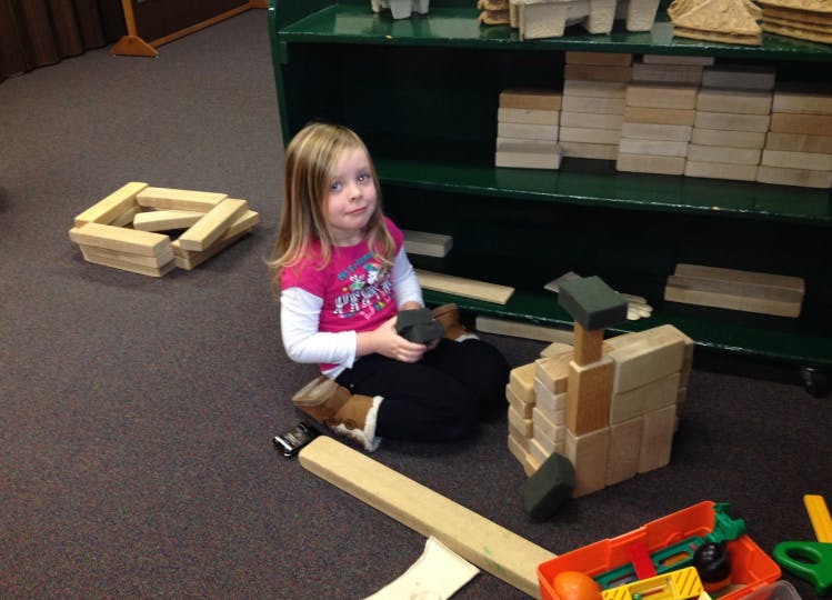 Child sitting on floor with wooden blocks