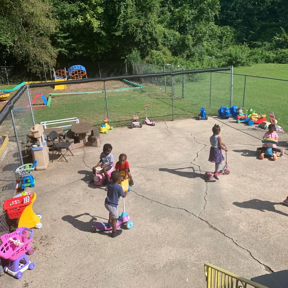 Children playing with scooters and toys on a paved area