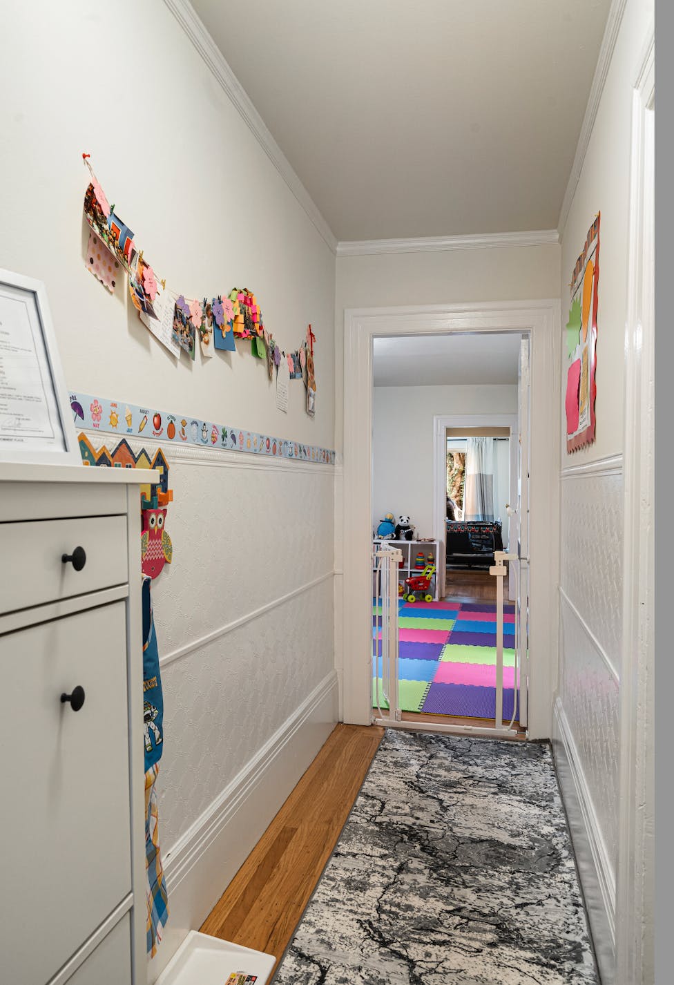 Hallway with children's artwork on the wall and a baby gate leading to a play area