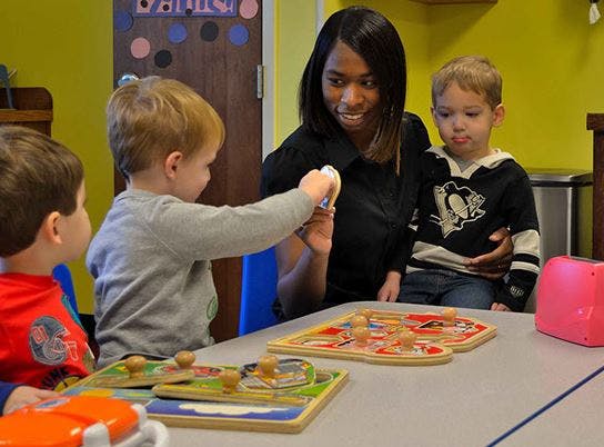 Adult and two children playing with puzzles at a table
