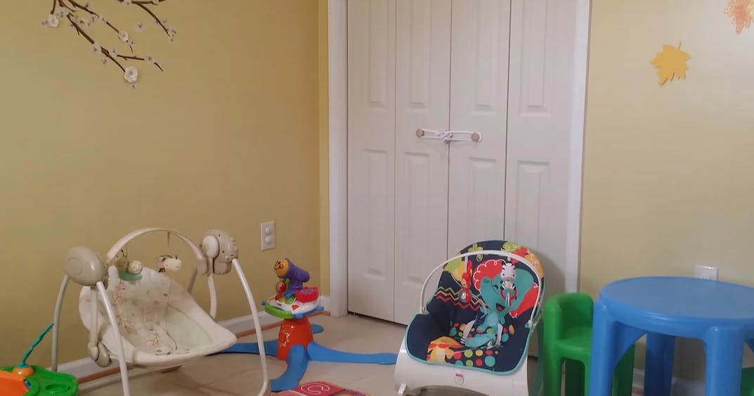 Baby swing and high chair in a room with a small table
