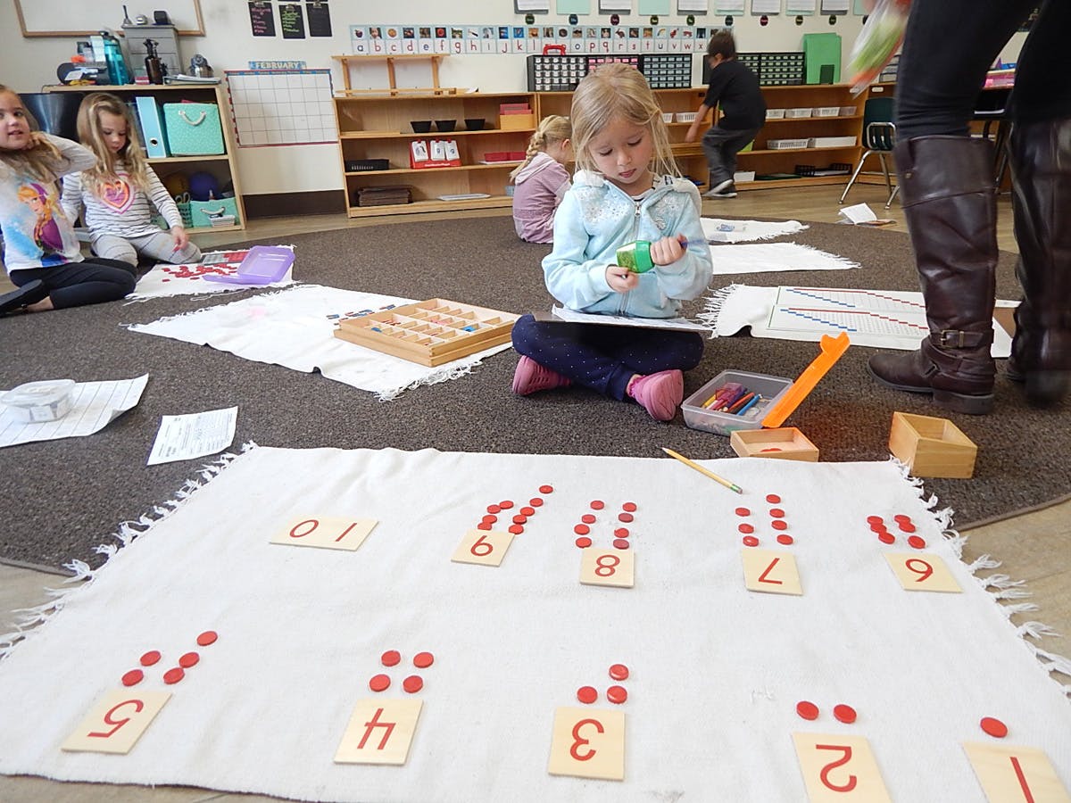 Child sitting on floor with number cards and red counters