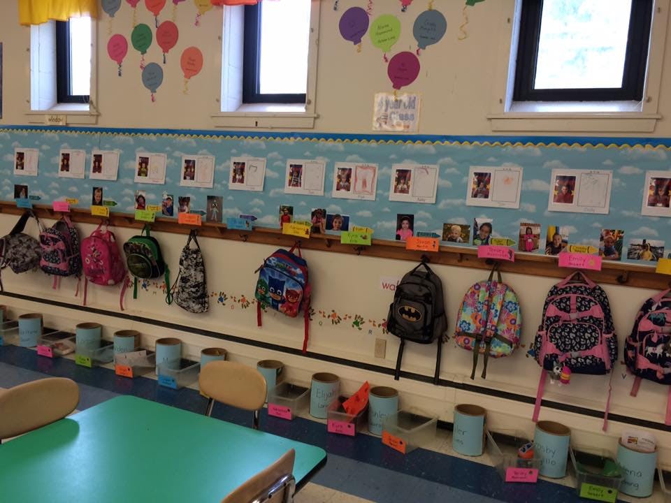 Backpacks hanging on hooks in a classroom