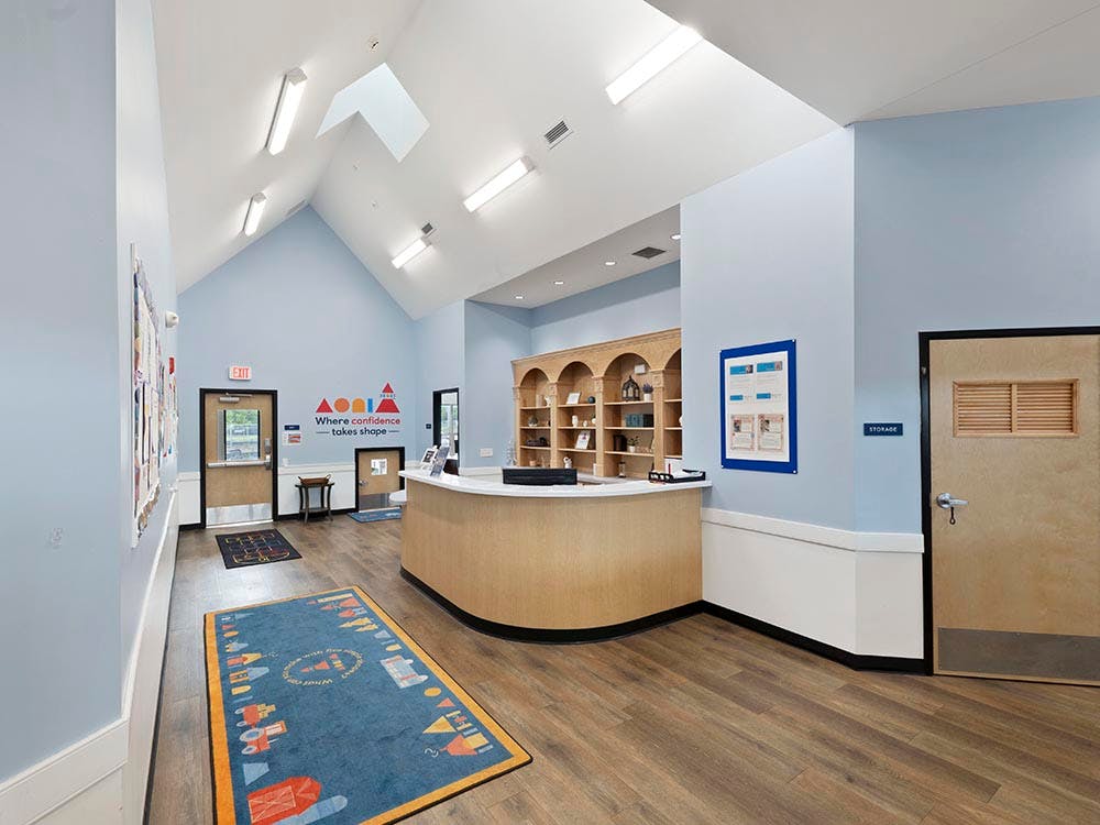 Reception area with a light wooden desk and a blue rug with an illustration