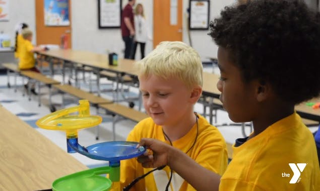 Two children playing with a colorful toy on a table