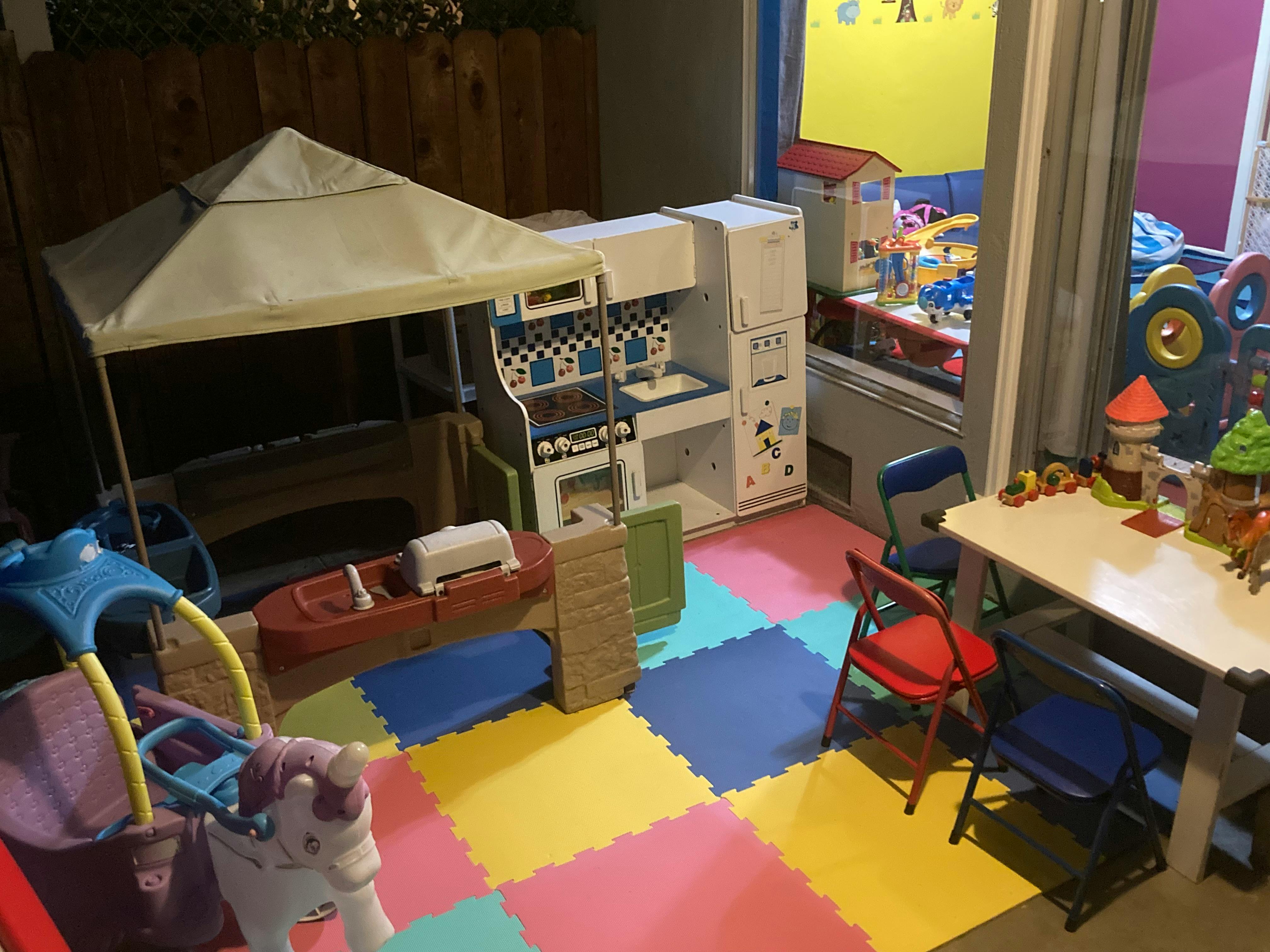 Playroom with colorful floor mats, play kitchen, and tent