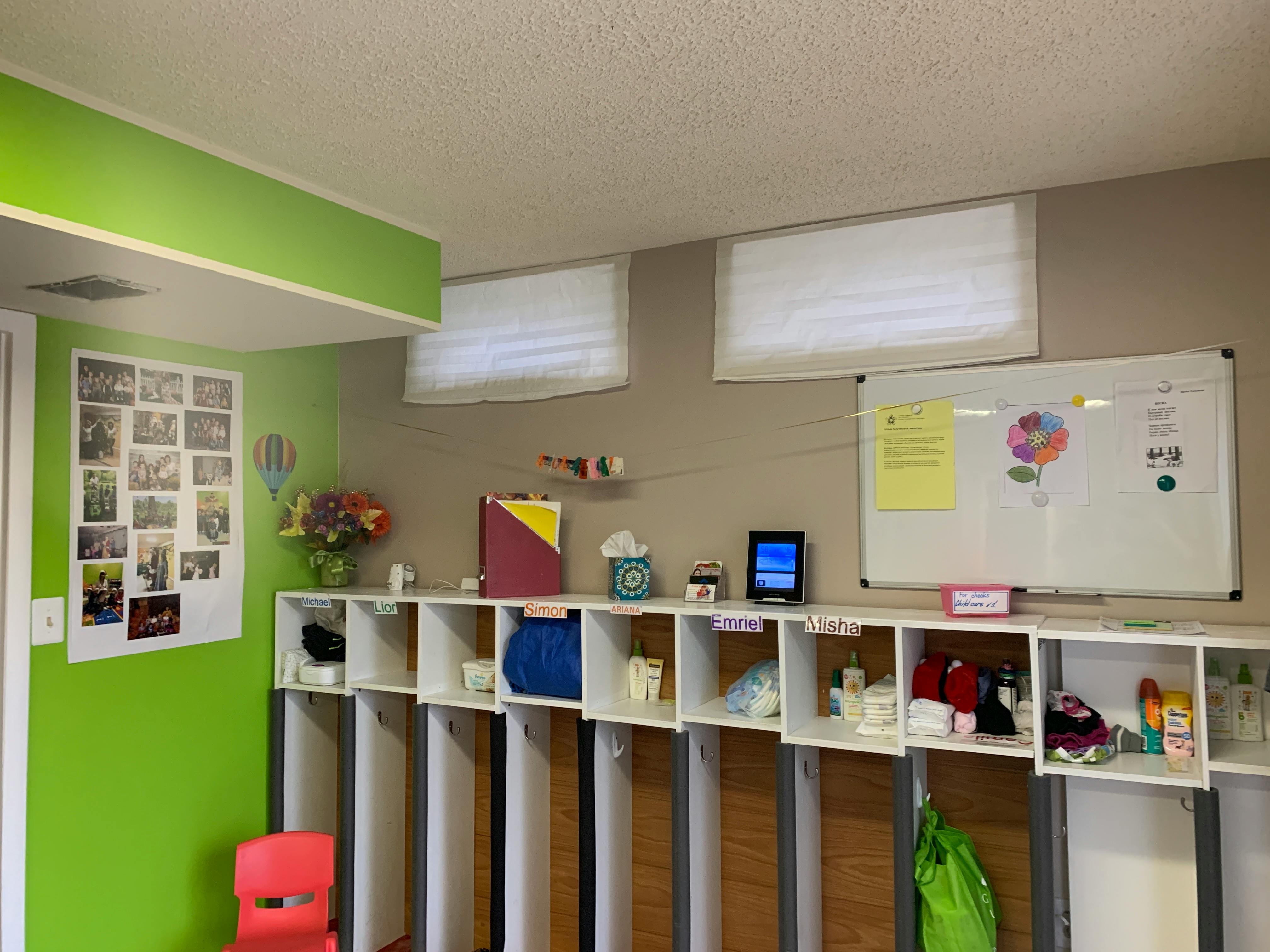 Storage cubbies with items and a whiteboard in a room