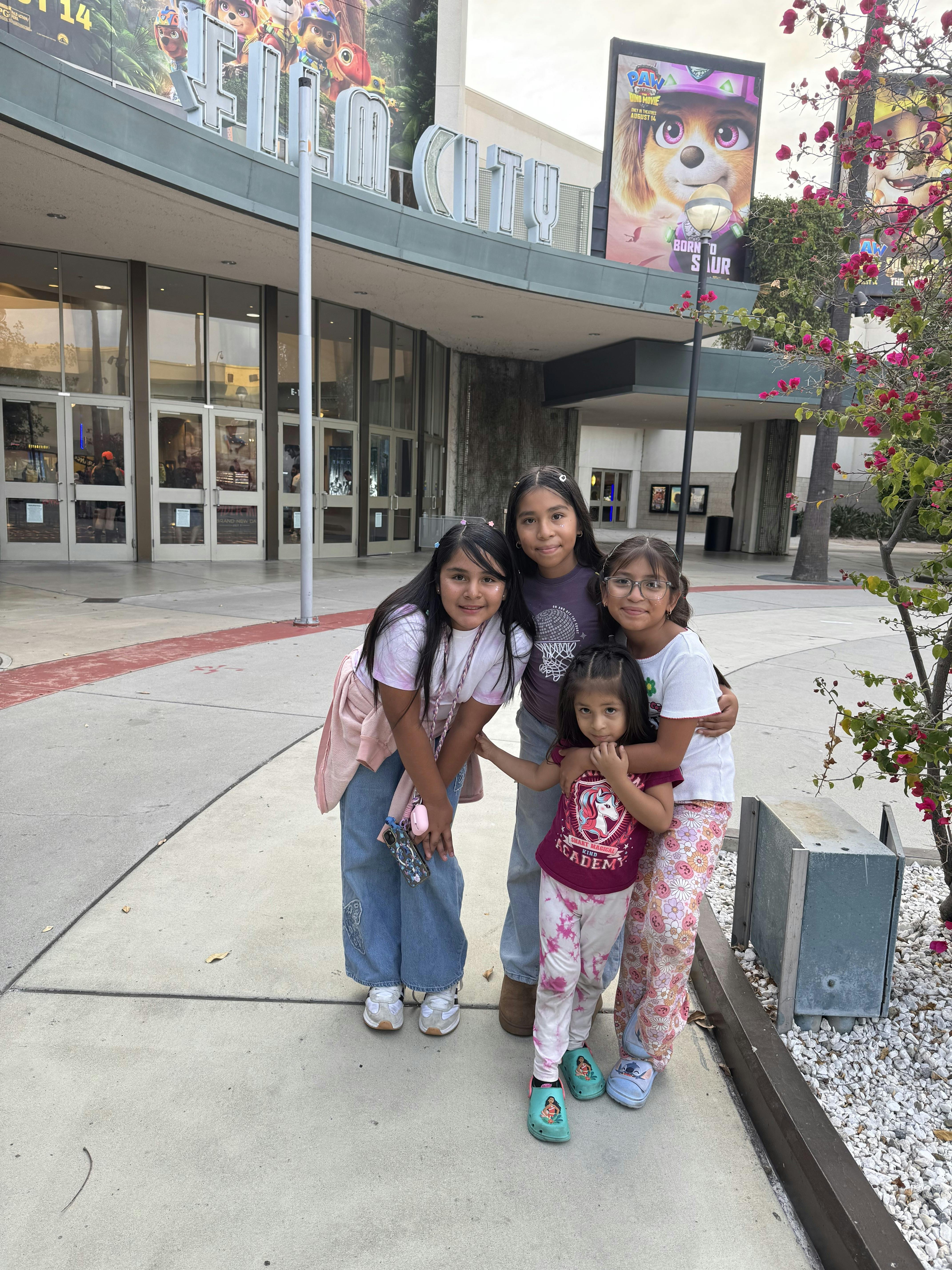 Four children standing together in front of a cinema building