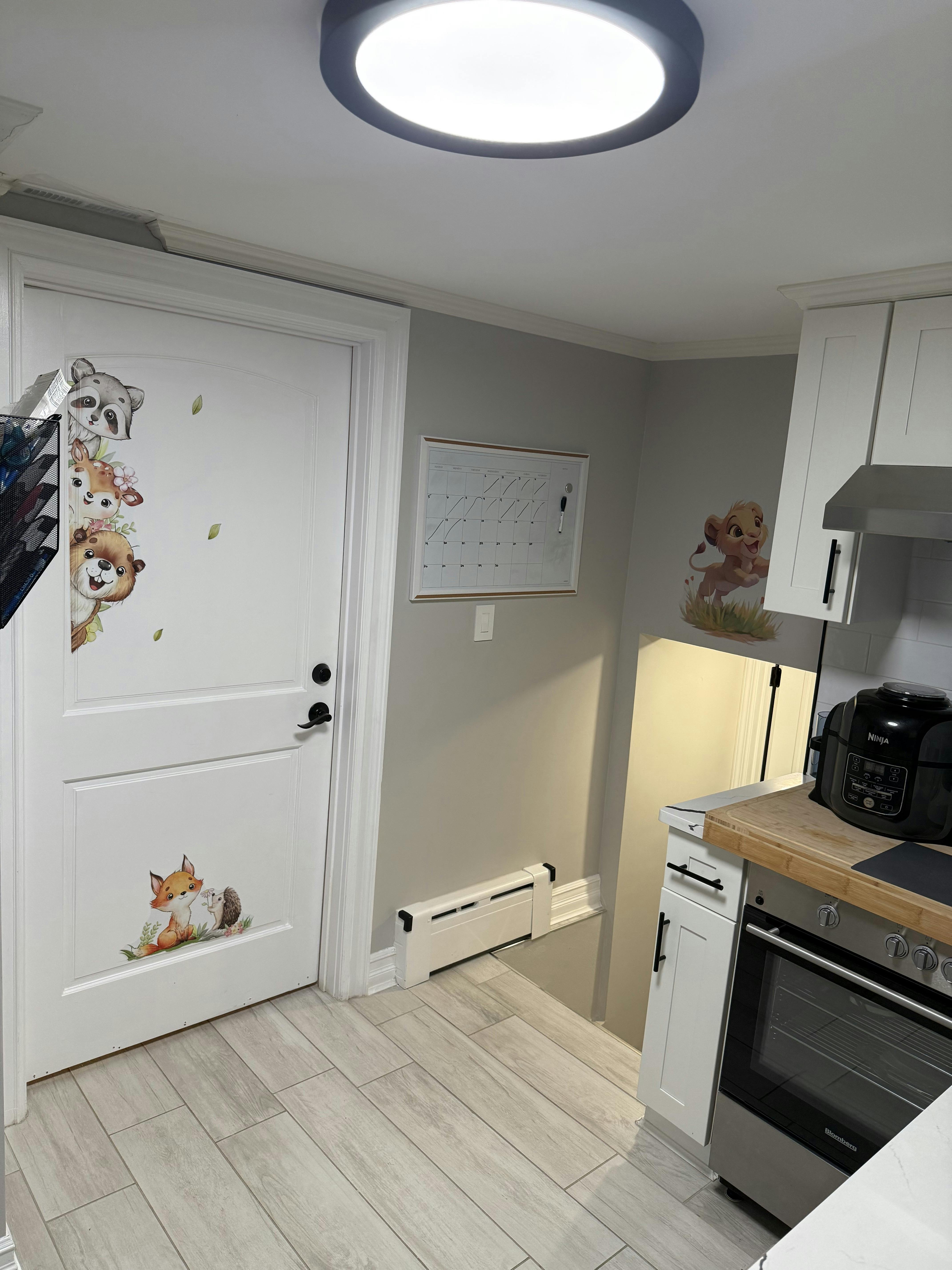 white kitchen with cartoon animal wall decals and a large round ceiling light