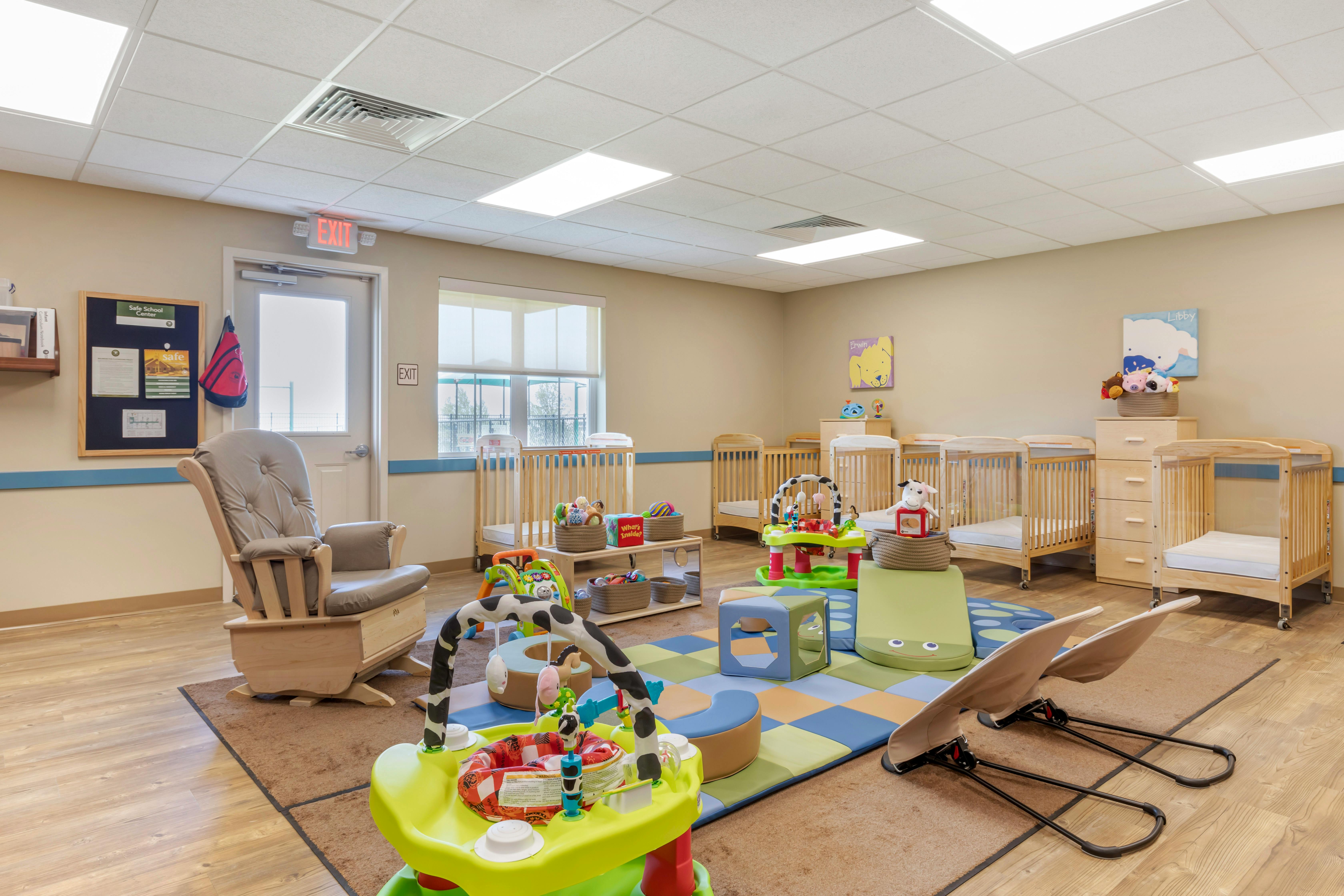 infant room with multiple cribs, a rocking chair, and play mats with toys