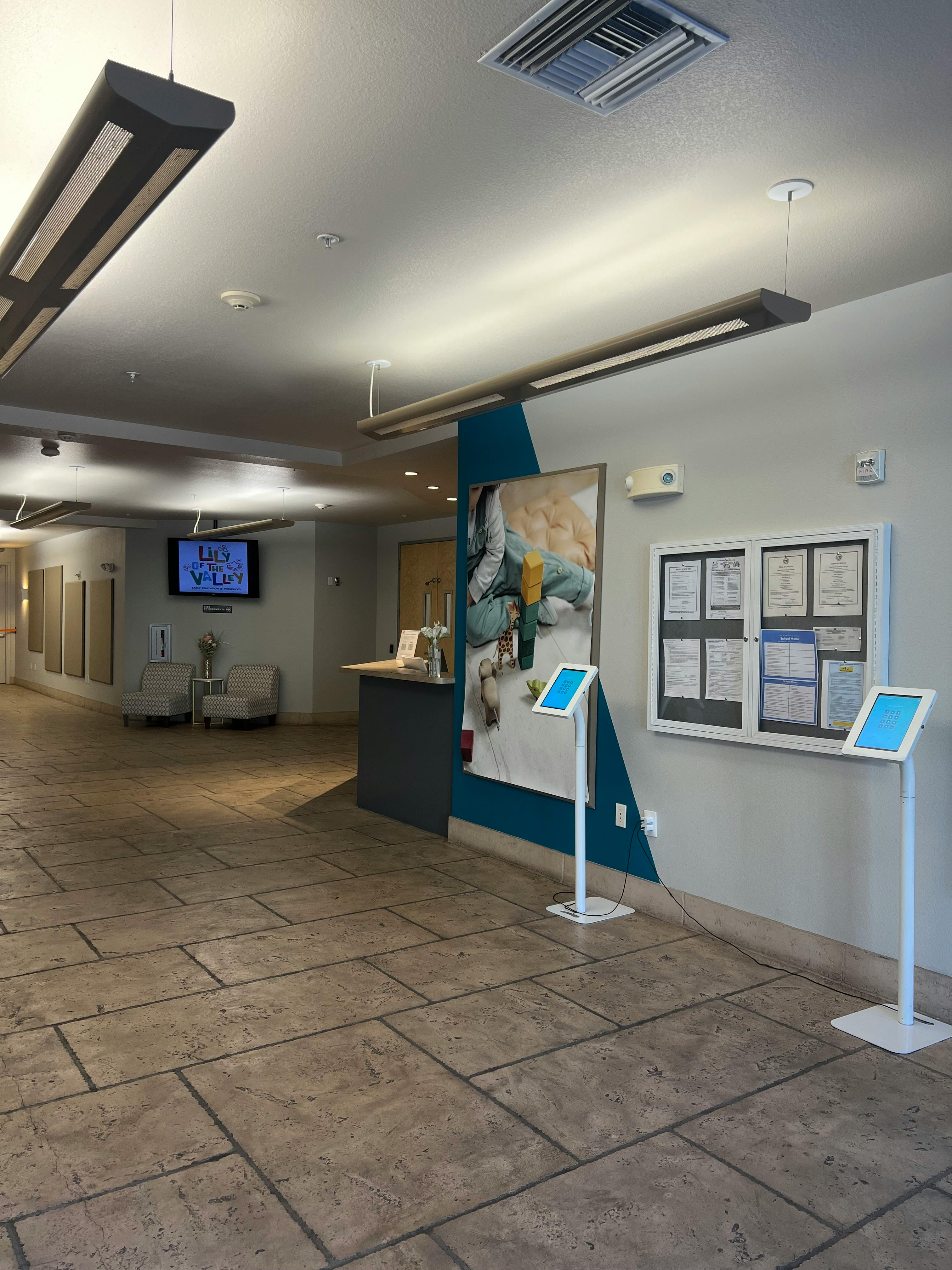 Lobby with a reception desk, bulletin board, and two digital kiosks