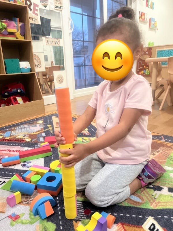 Child kneeling on a rug, playing with colorful foam blocks