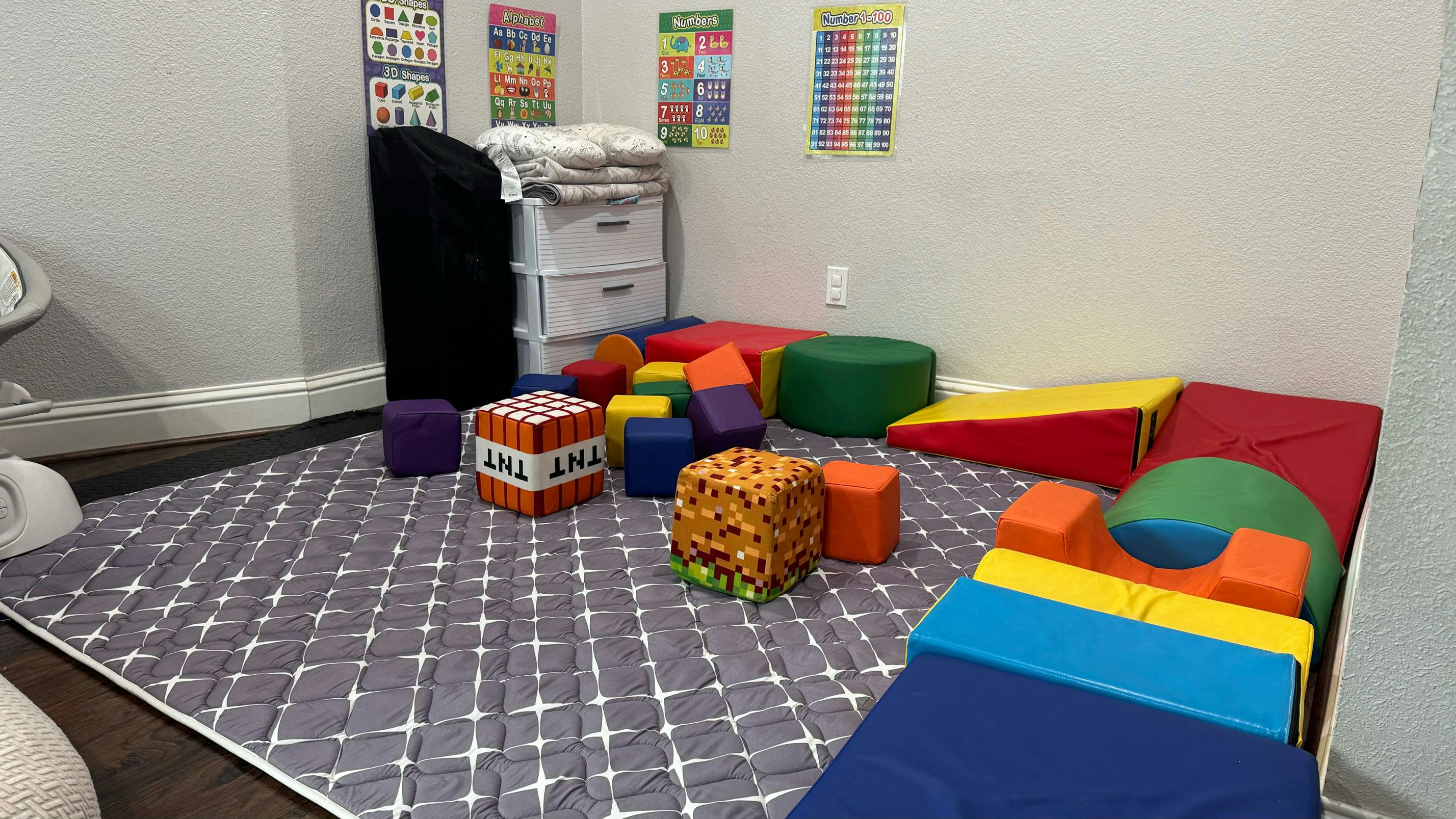 indoor play area with a gray mat and colorful soft play blocks and cushions