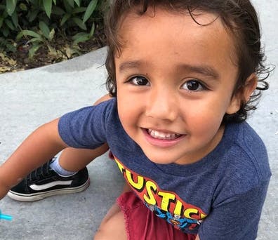 Child in a blue shirt with "JUSTICE" text smiling