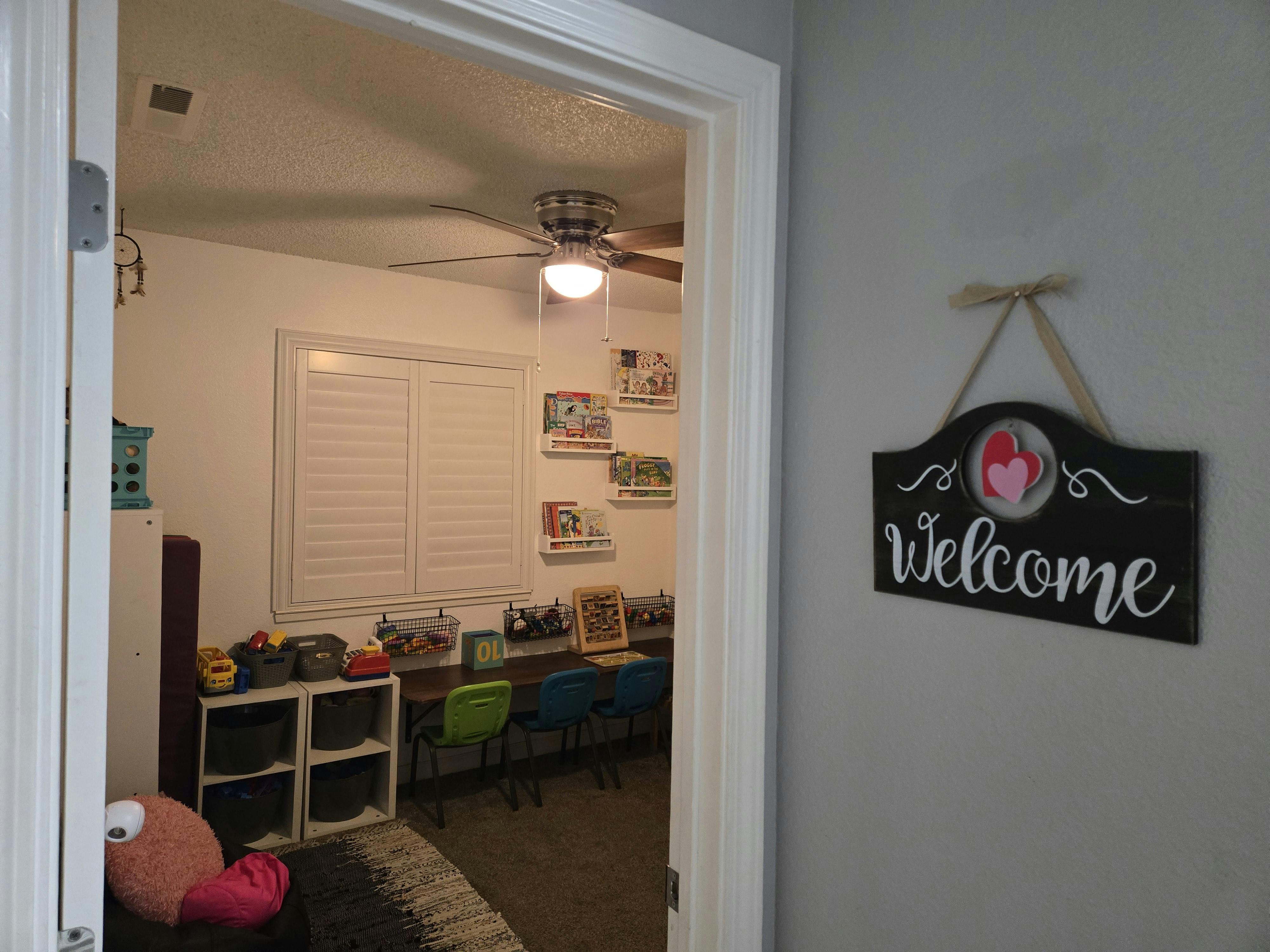 Welcome sign on a wall next to an open doorway leading to a room