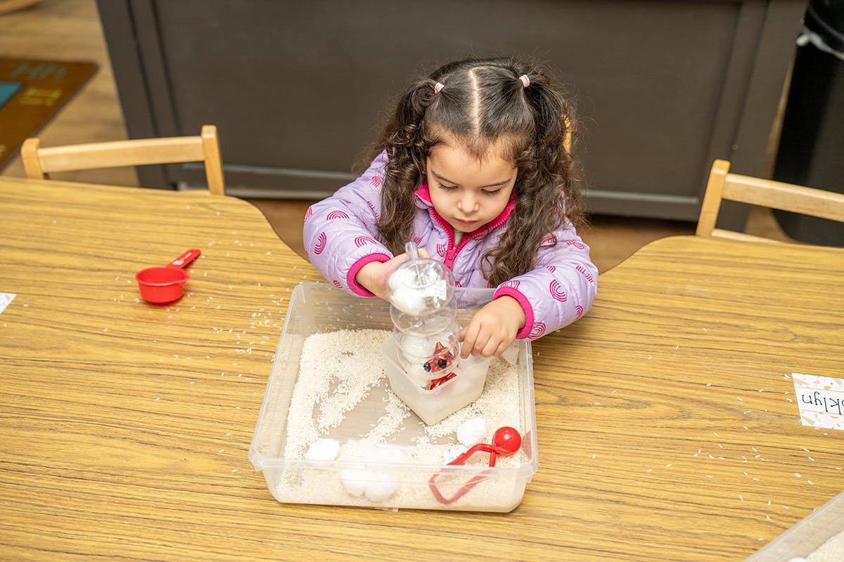 Child playing with sensory bin at a table