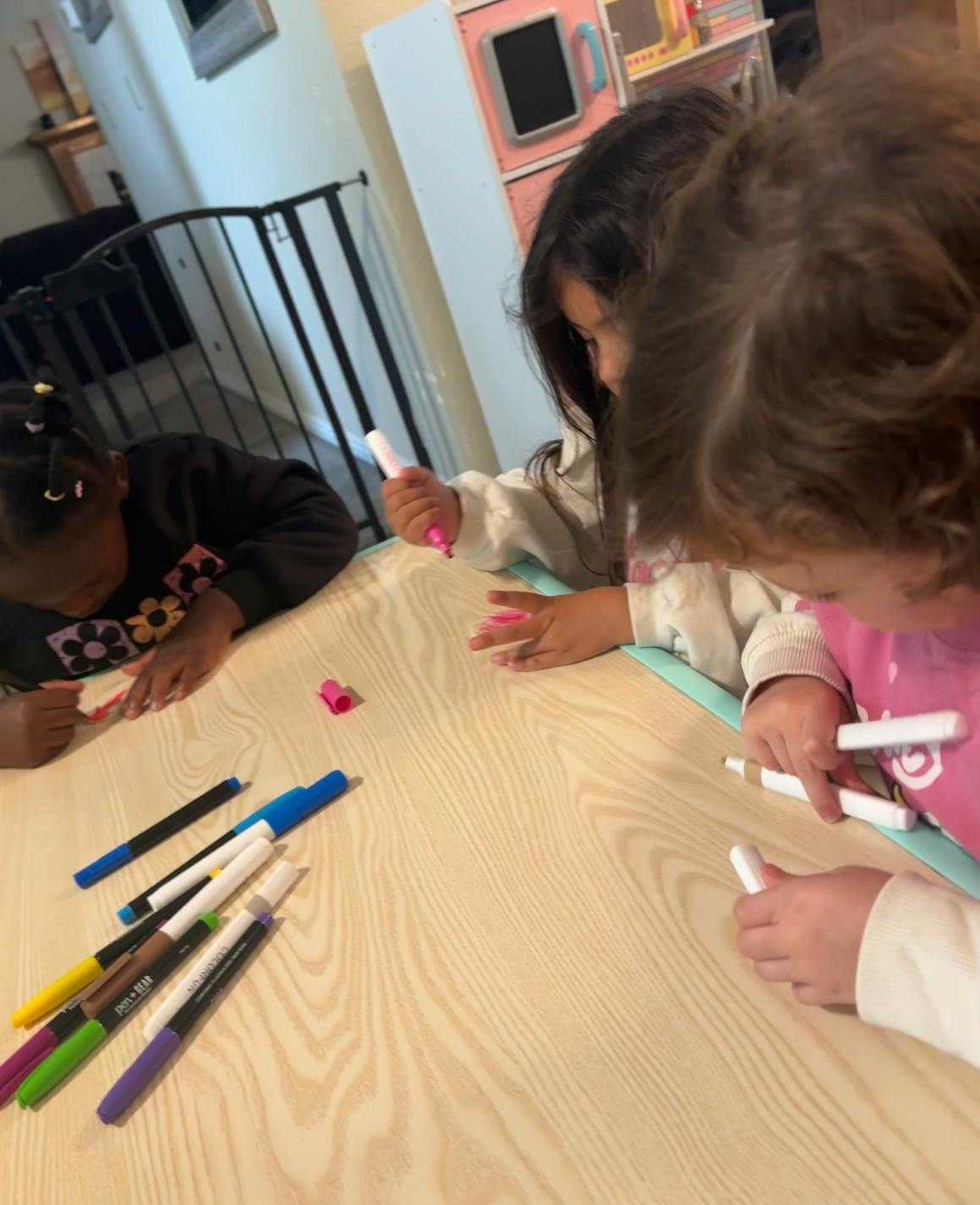 Three children drawing with markers at a table