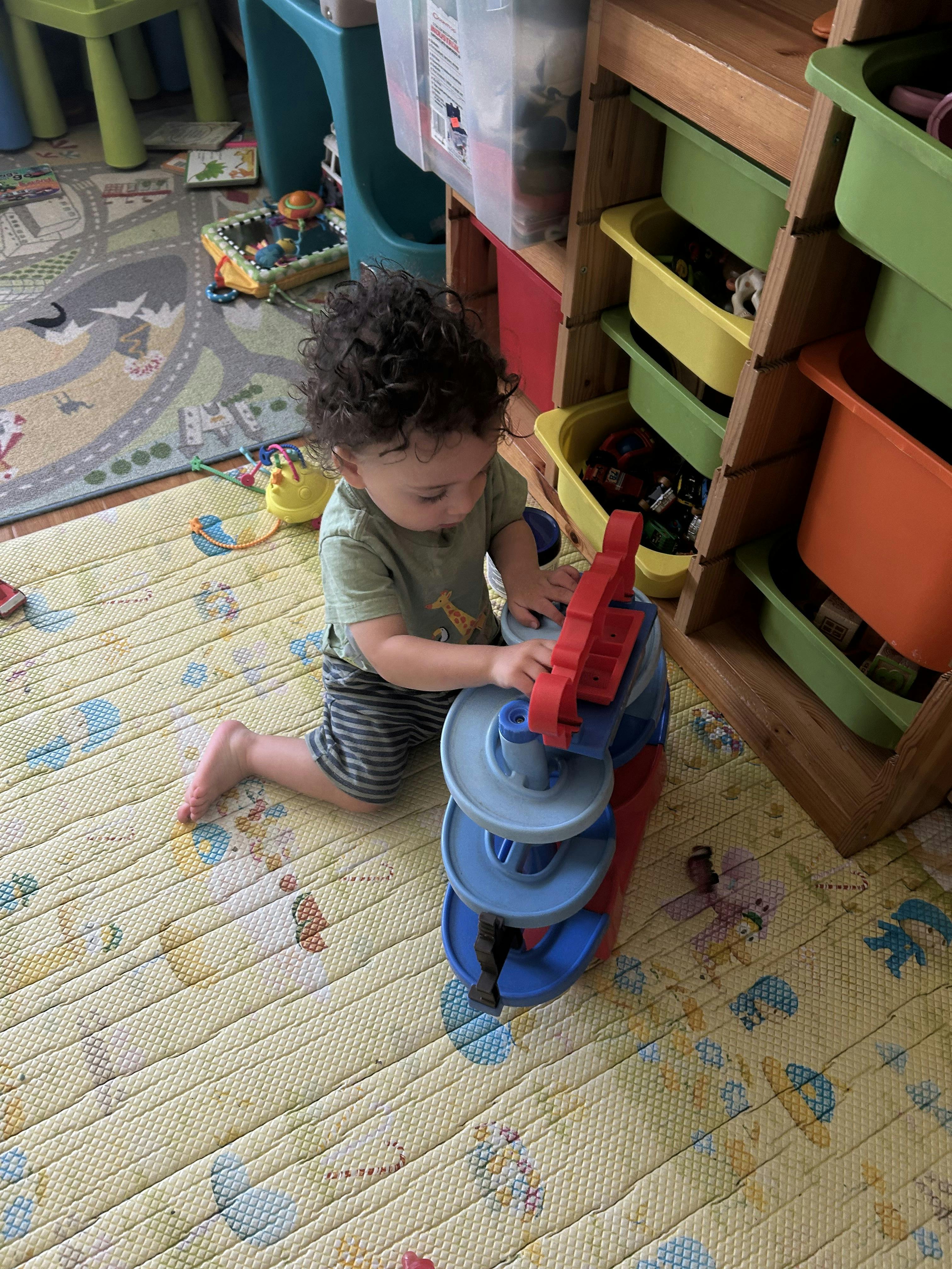 Child playing with a toy ramp on a mat