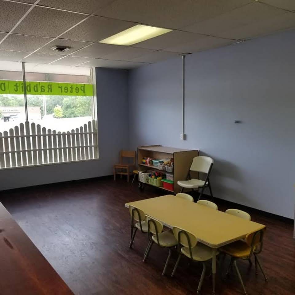 Empty classroom with small table and chairs, storage unit, and window