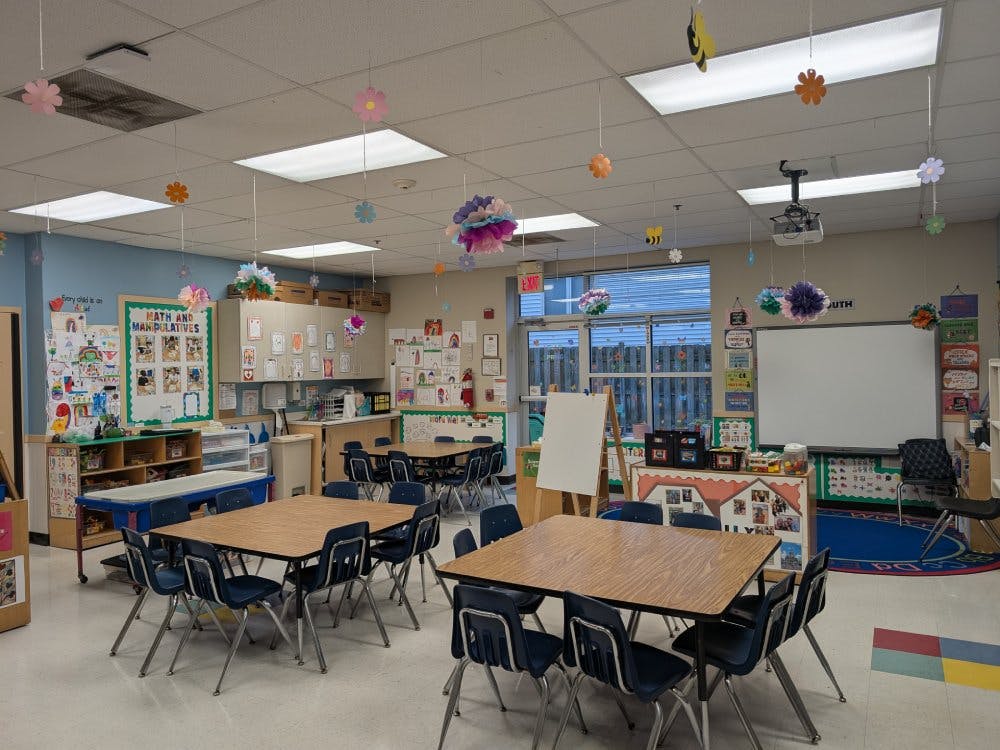 Empty classroom with small tables and chairs, decorated ceiling