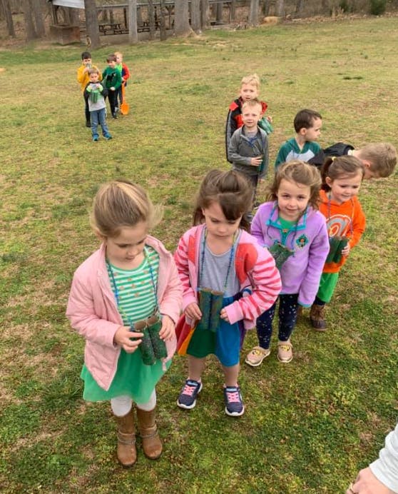 Children standing in a line outdoors, some holding binoculars