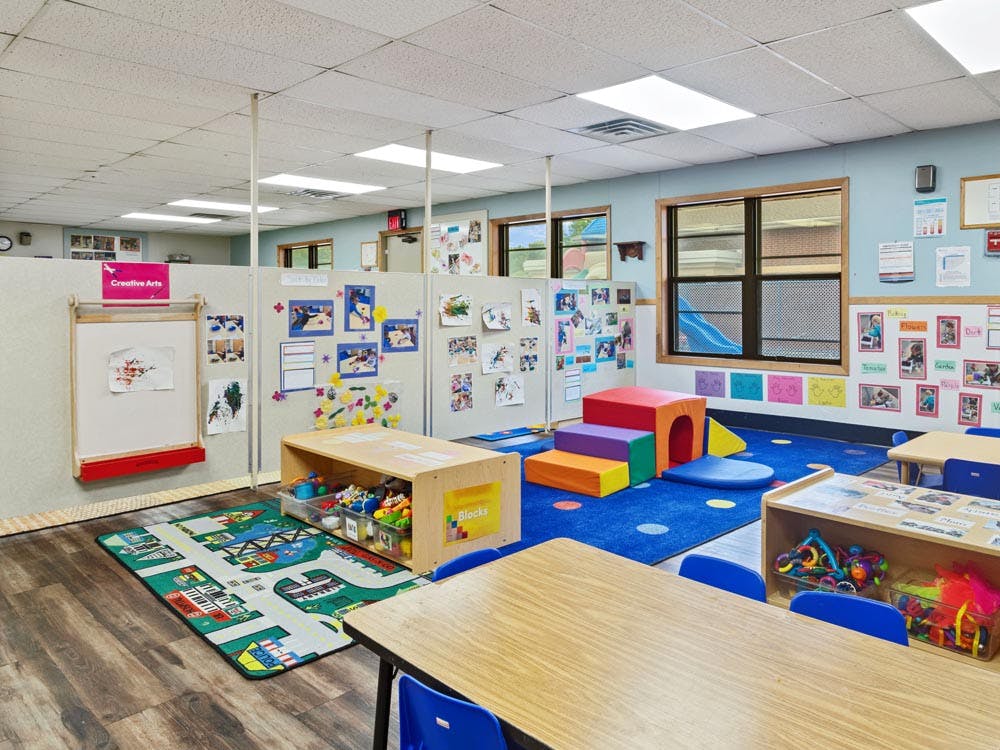 Classroom with play areas, small tables, and art displayed on walls