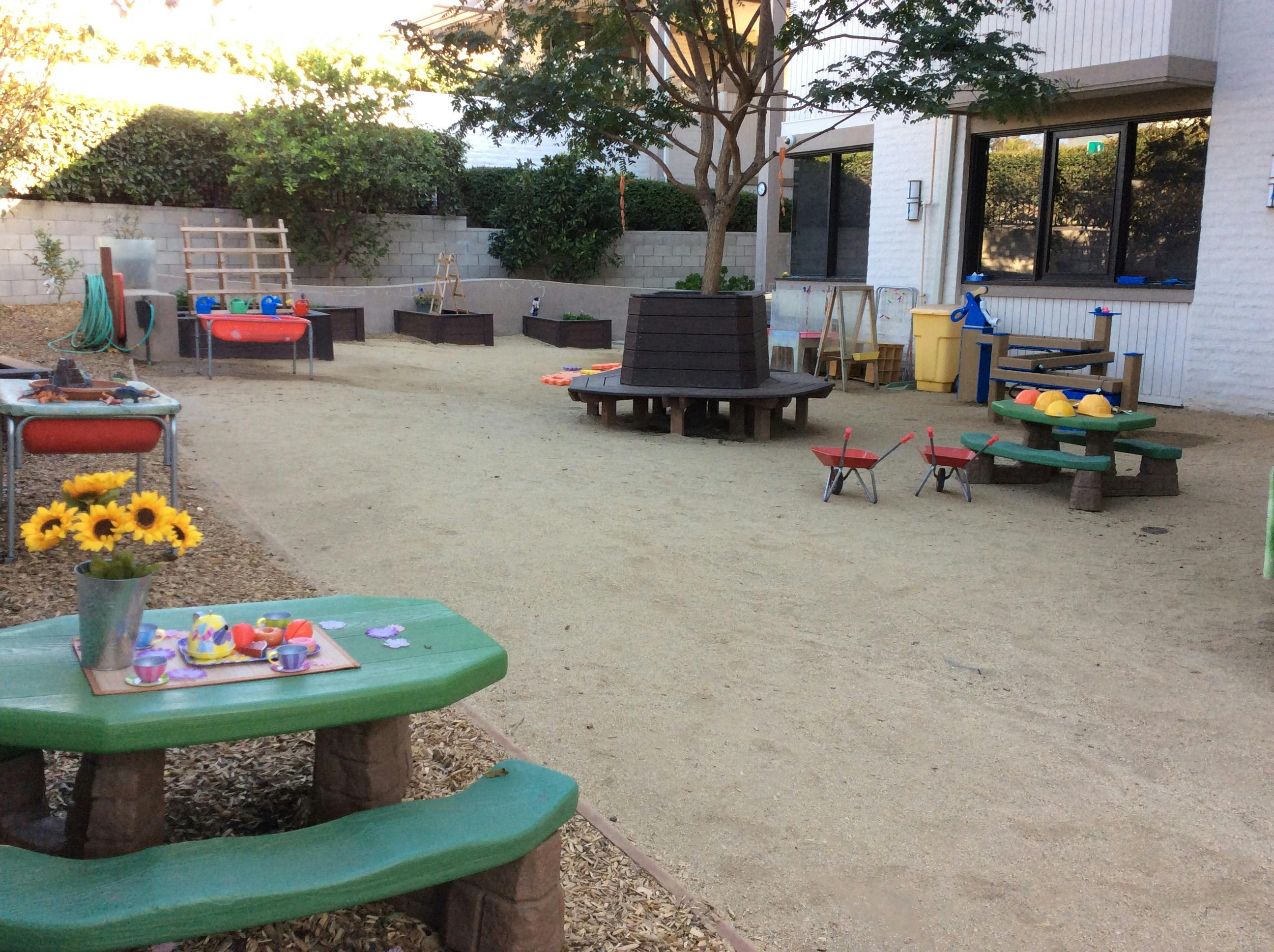 Outdoor play area with sand, picnic tables, and various play equipment