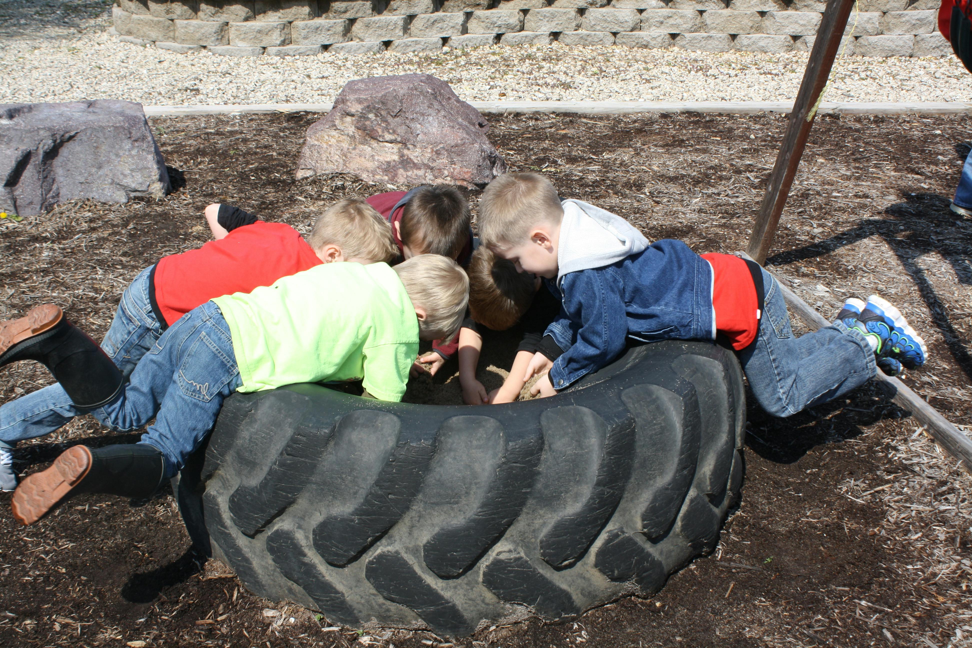 Children looking into a large tire