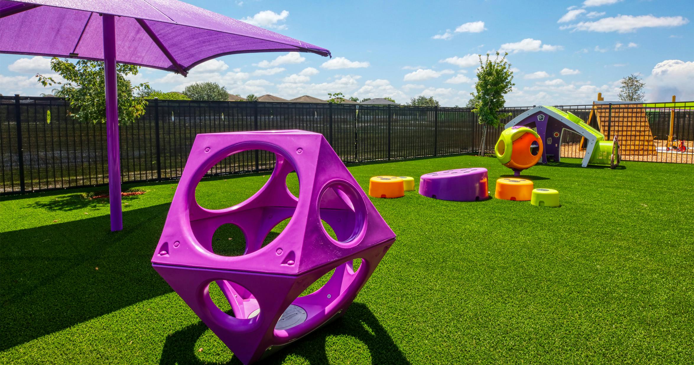 Purple play structure on green artificial turf